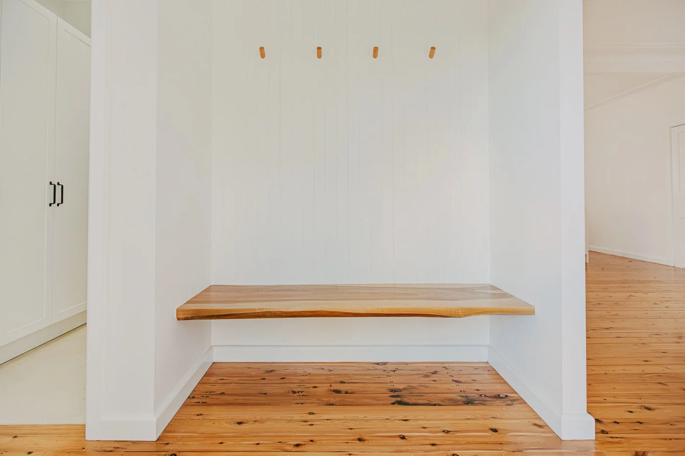 Built-in mudroom storage with timber bench, wall hooks and hardwood flooring in a Thornleigh home featuring custom extension work
