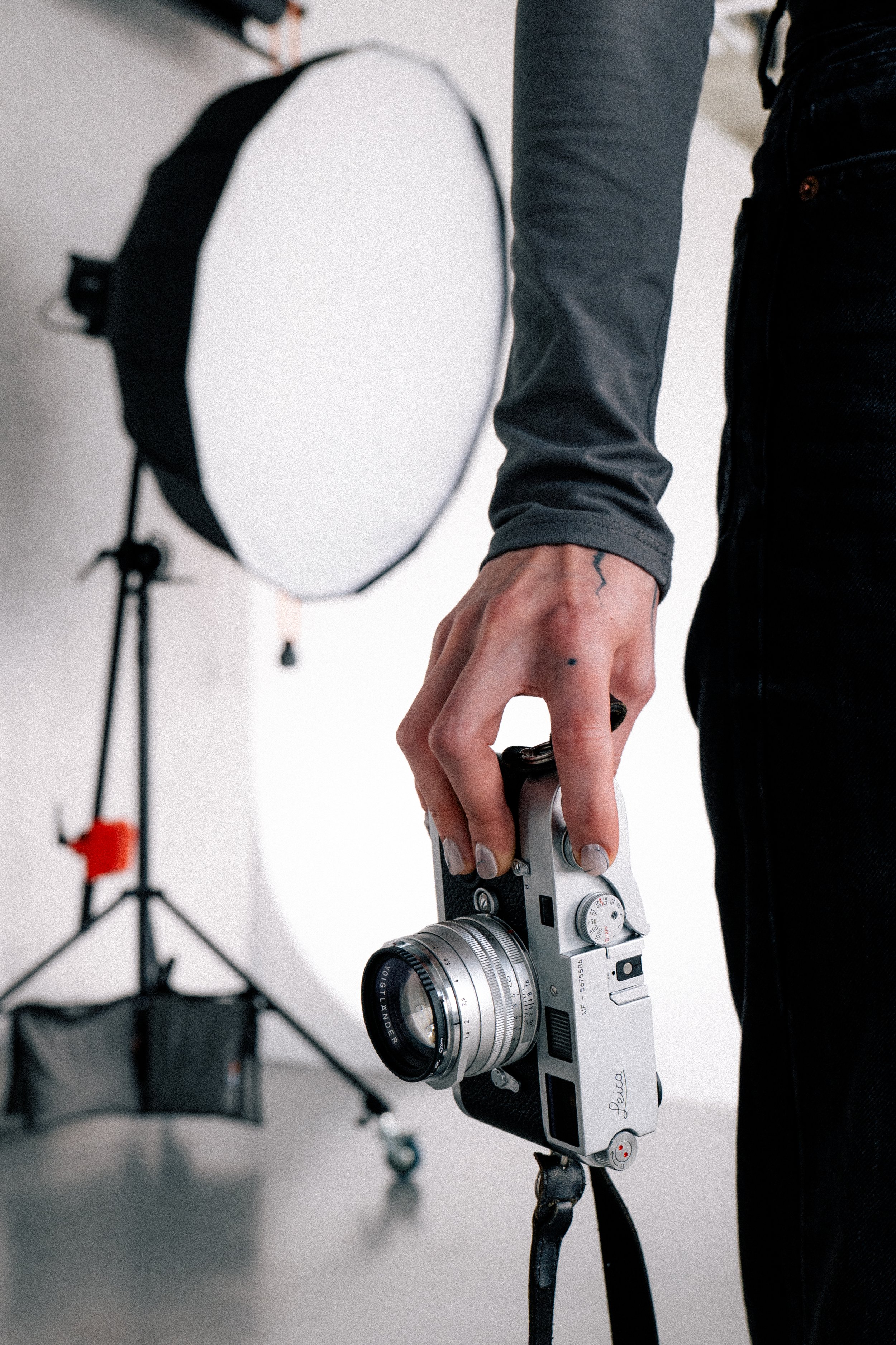 Person holding a vintage film camera in a photography studio with professional lighting equipment in the background.