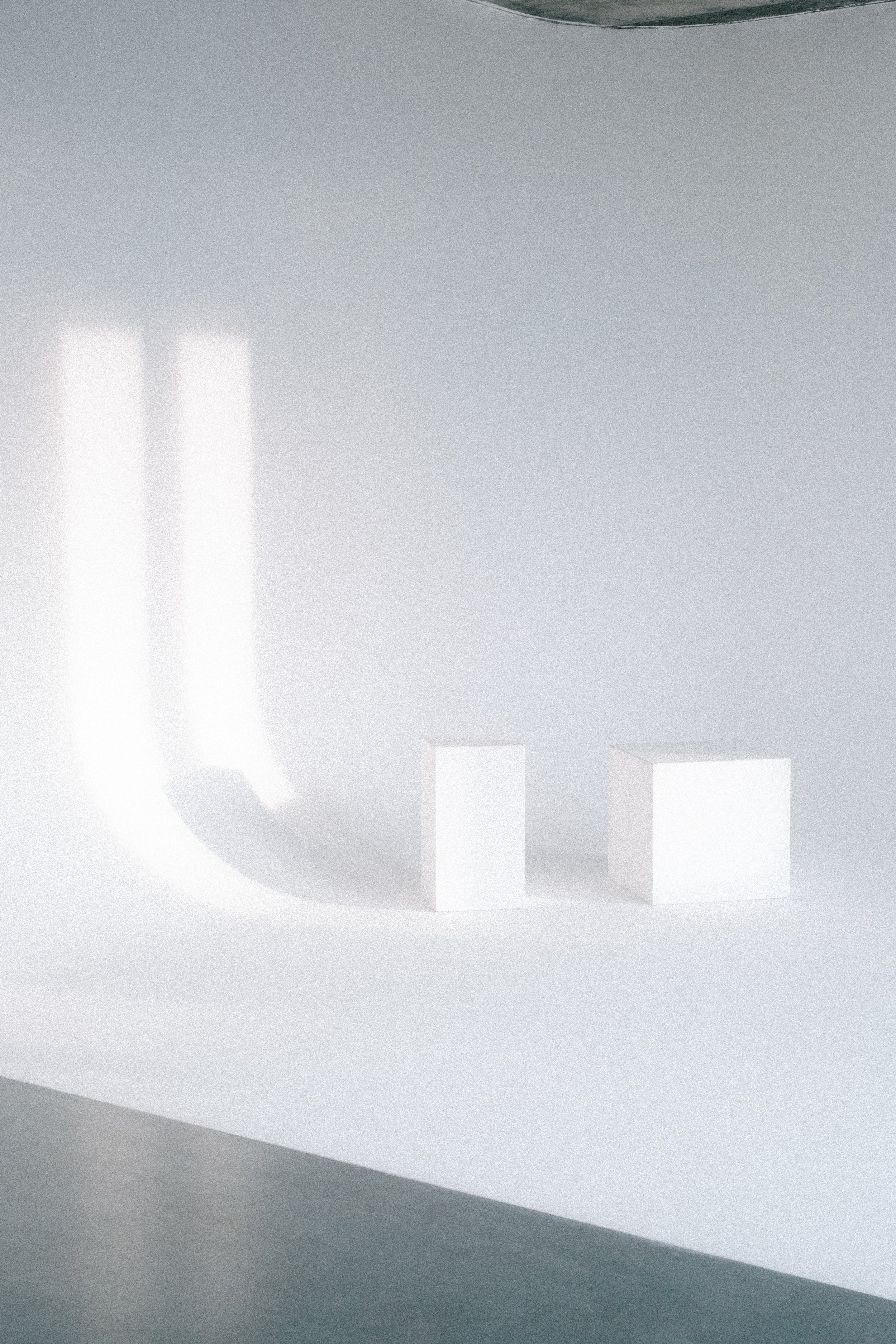 Three white rectangular blocks of different heights on a white surface with soft shadows, with a light gray background.