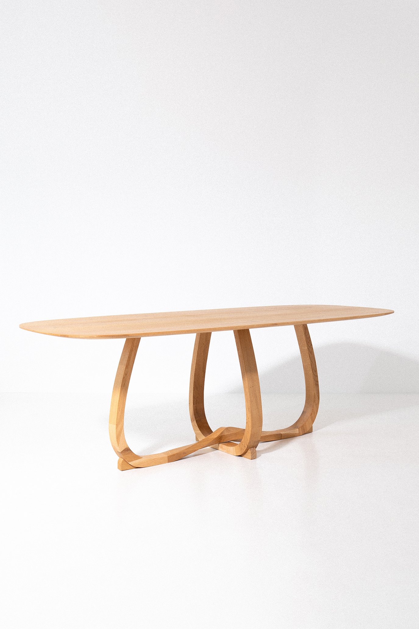 A modern wooden table with curved legs and a flat top, placed against a white background.