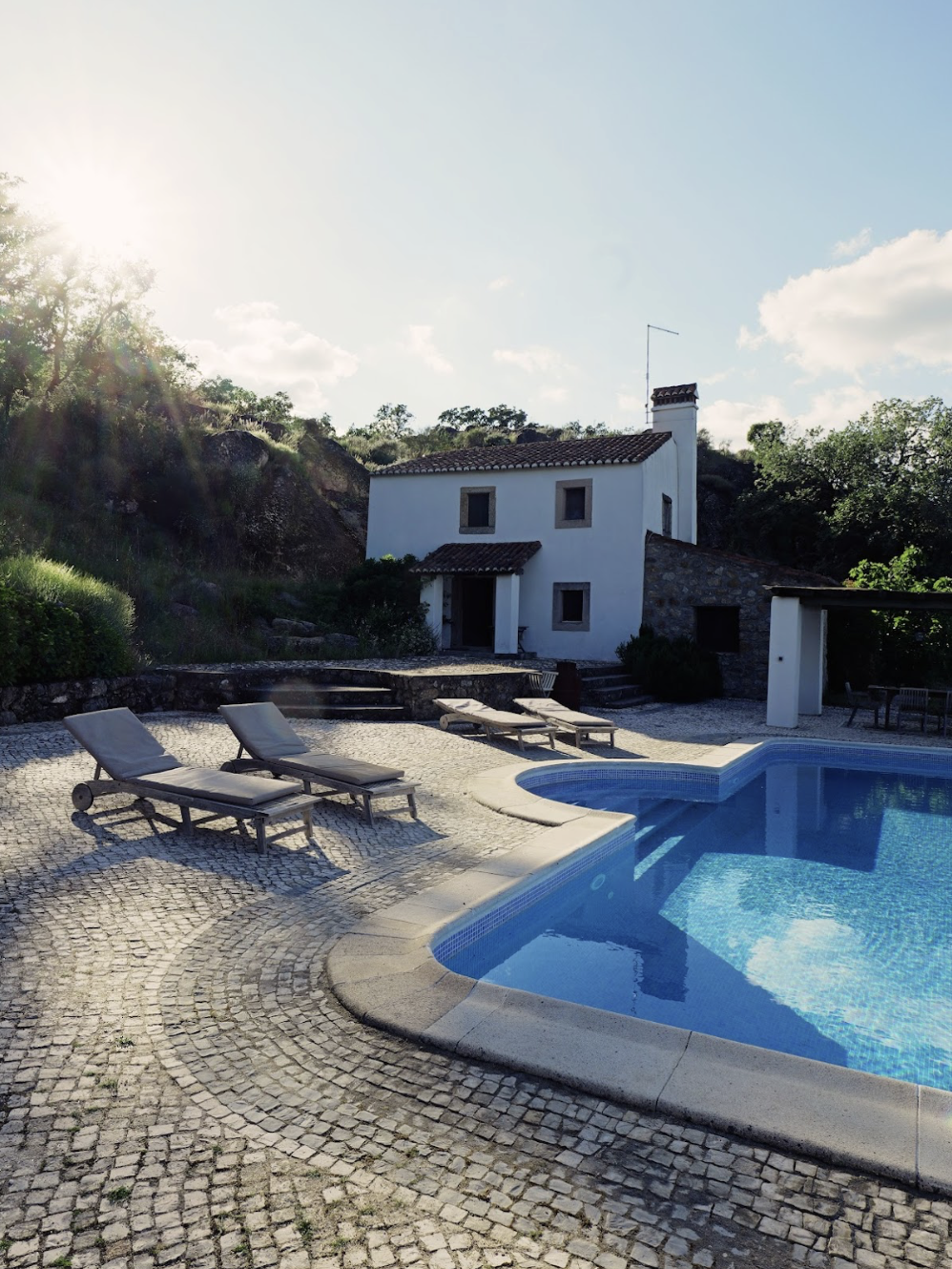infinity swimming pool sun beds and house in the background