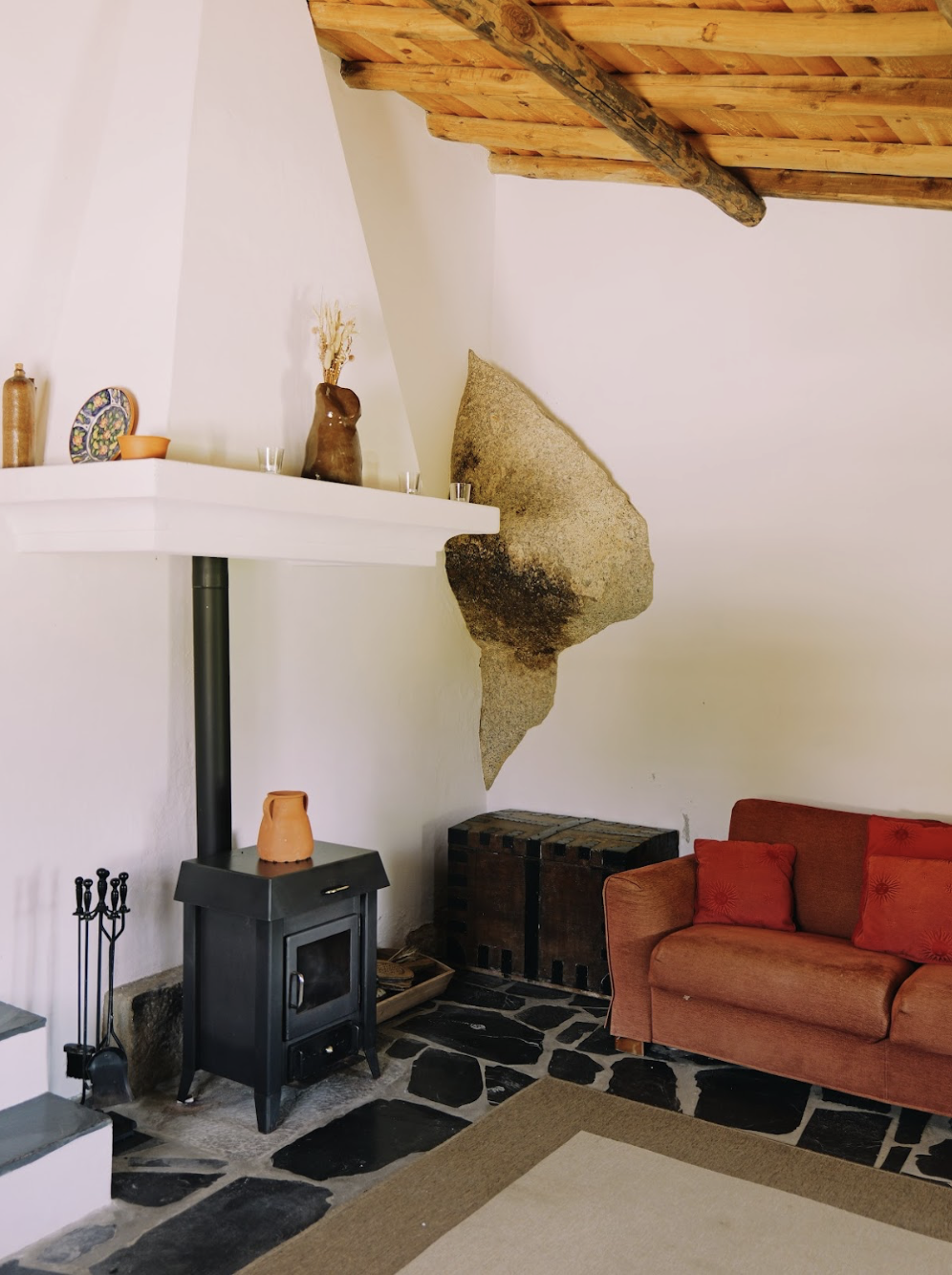 living room with wood burner fire place and natural stone appearing through the walls