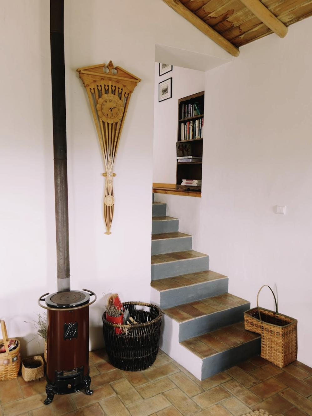 wood burner stove and designer clock beside stairs leading from living room to the bedrooms and bathroom
