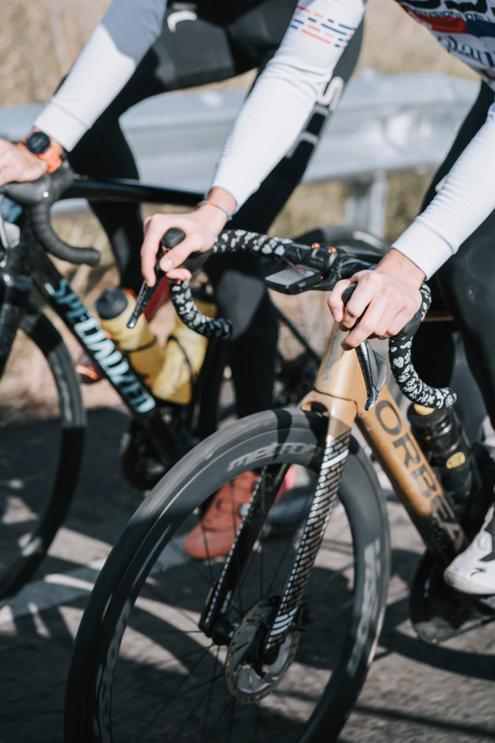 Close-up of two cyclists' hands gripping bicycle handlebars during a race.