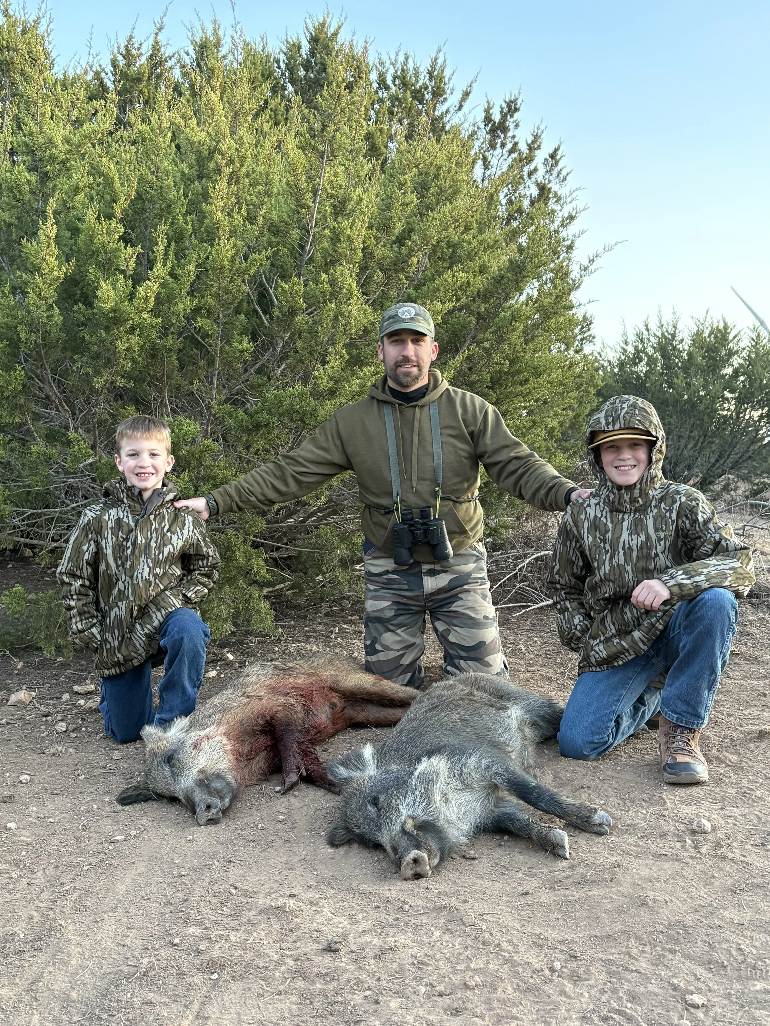 Father and sons after successful hog hunt in the field