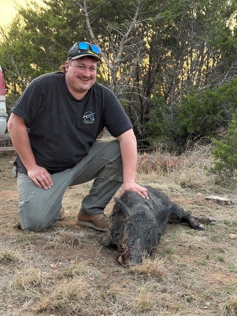 Hunter poses with wild hog in the pasture