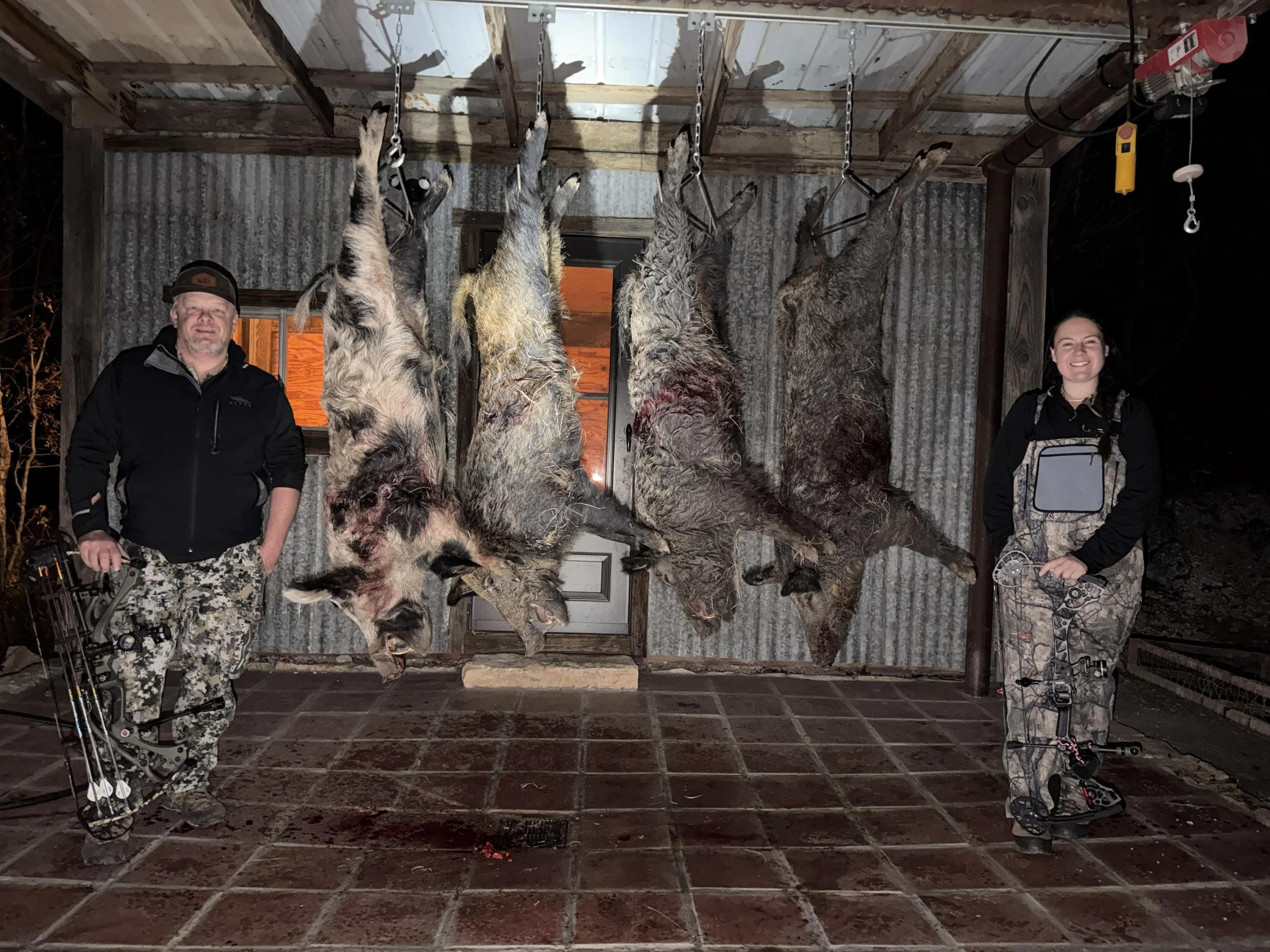Bow hunters at night posing with trophy boars