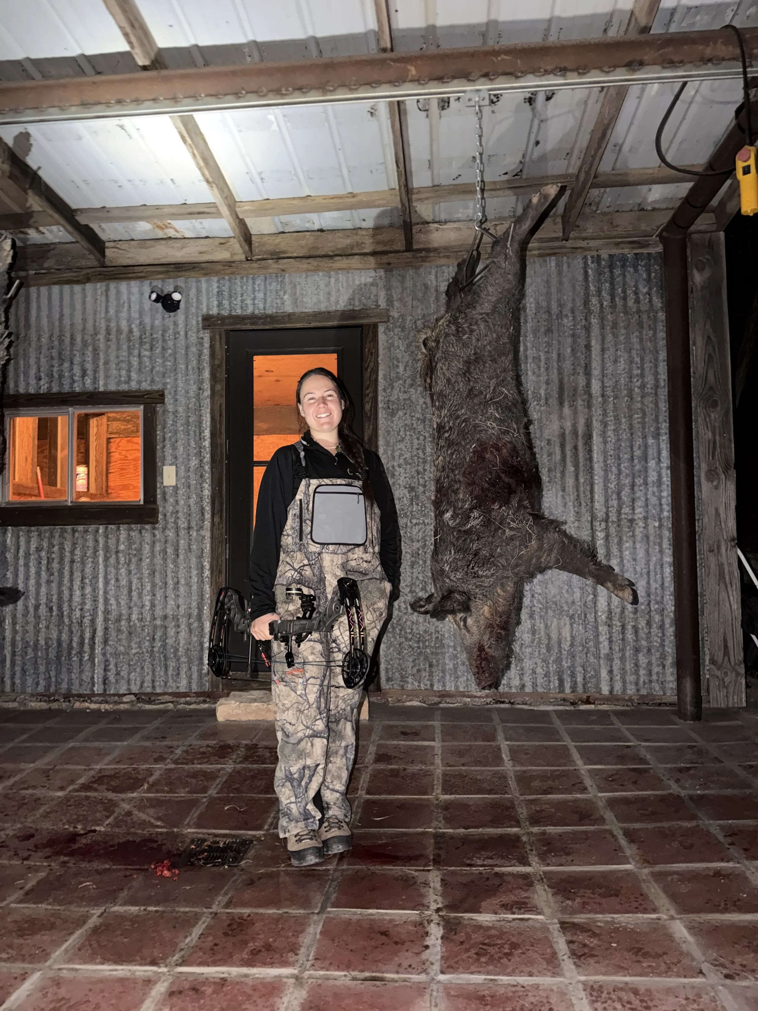 Bow hunter posing with wild hog