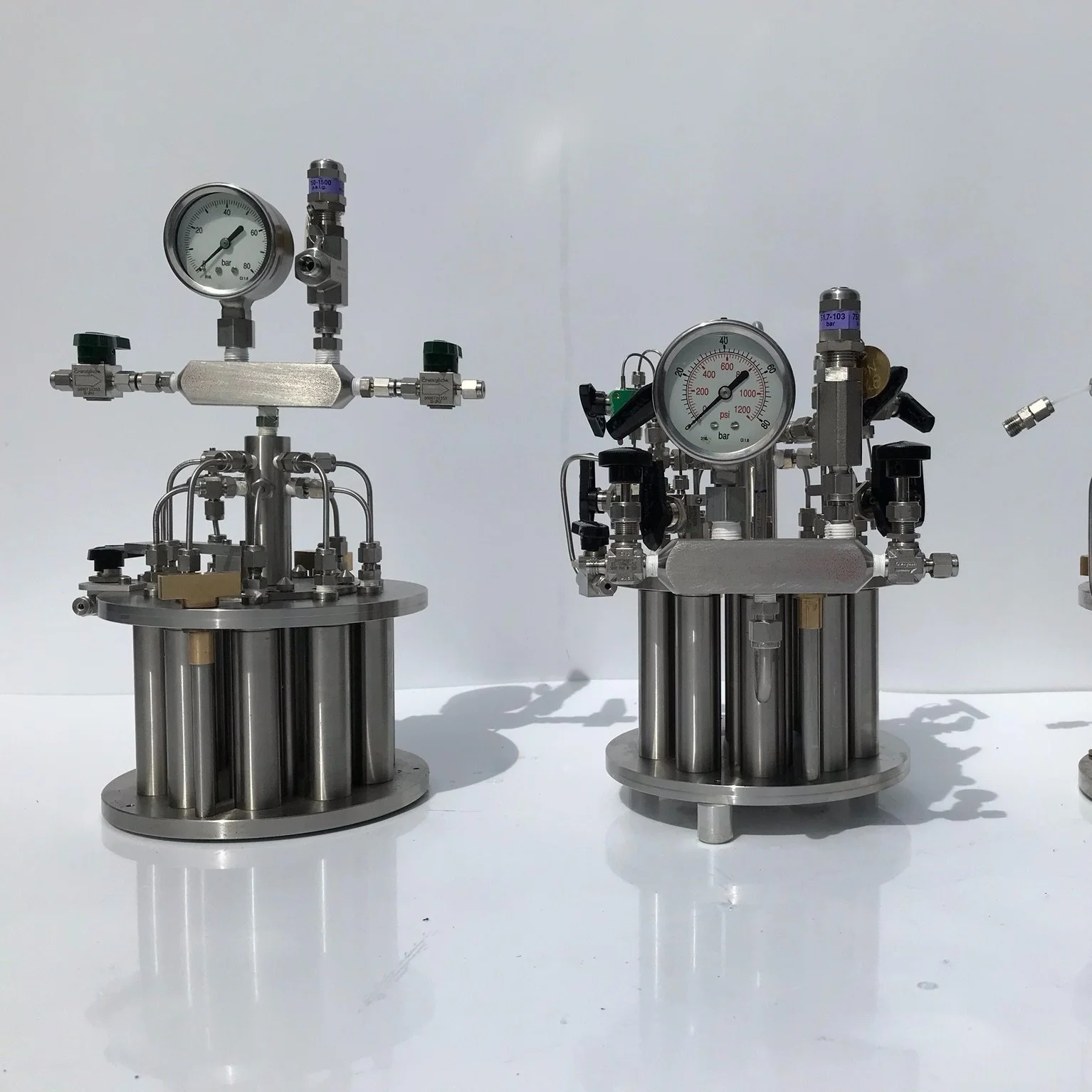 Two stainless steel industrial pressure regulators with gauges and valves, set against a plain white background.