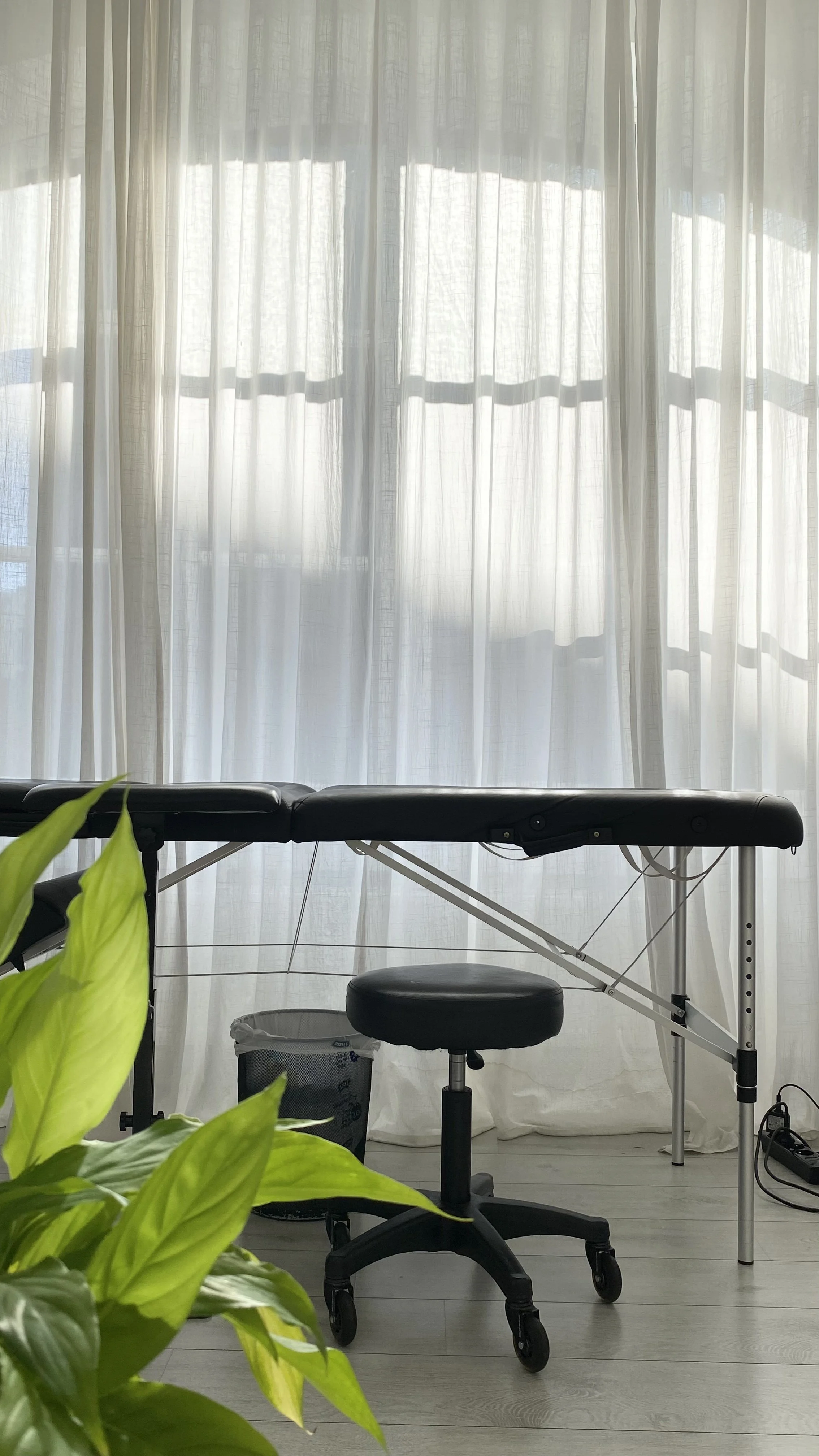 Table de massage et tabouret dans un espace intime et confortable du studio à Bruxelles