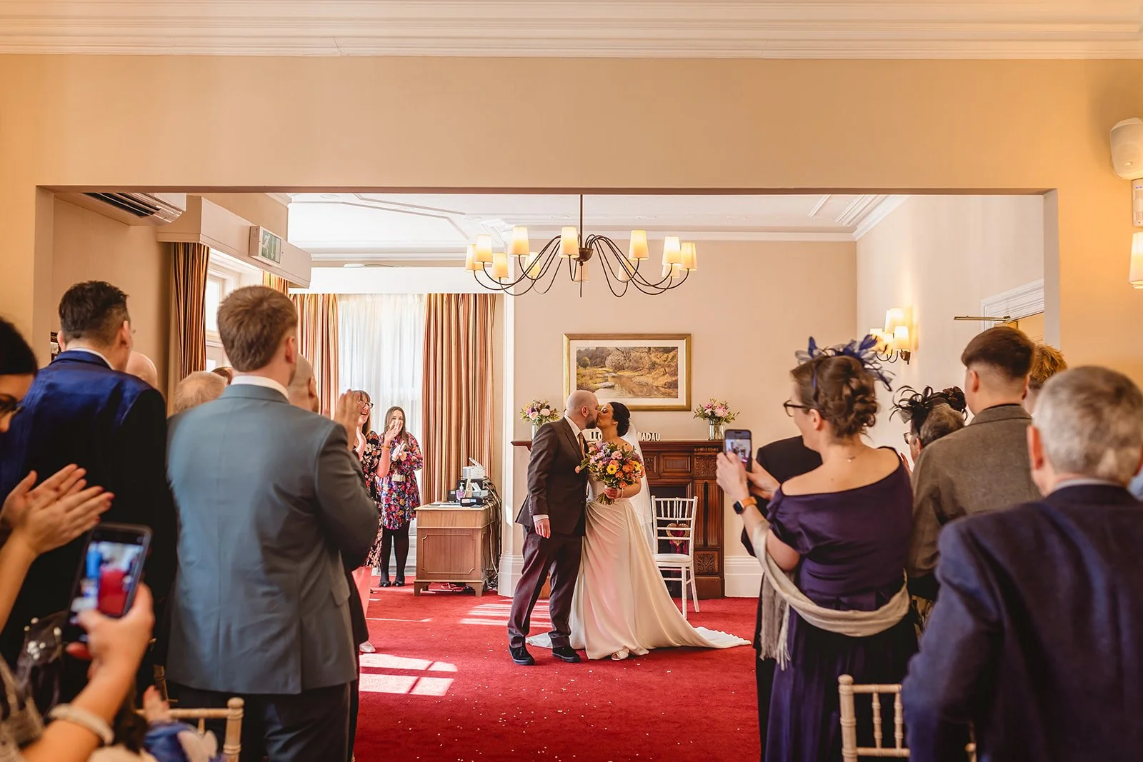 couple close their wedding ceremony with a kiss as their guests clap and cheer at newport mansion house