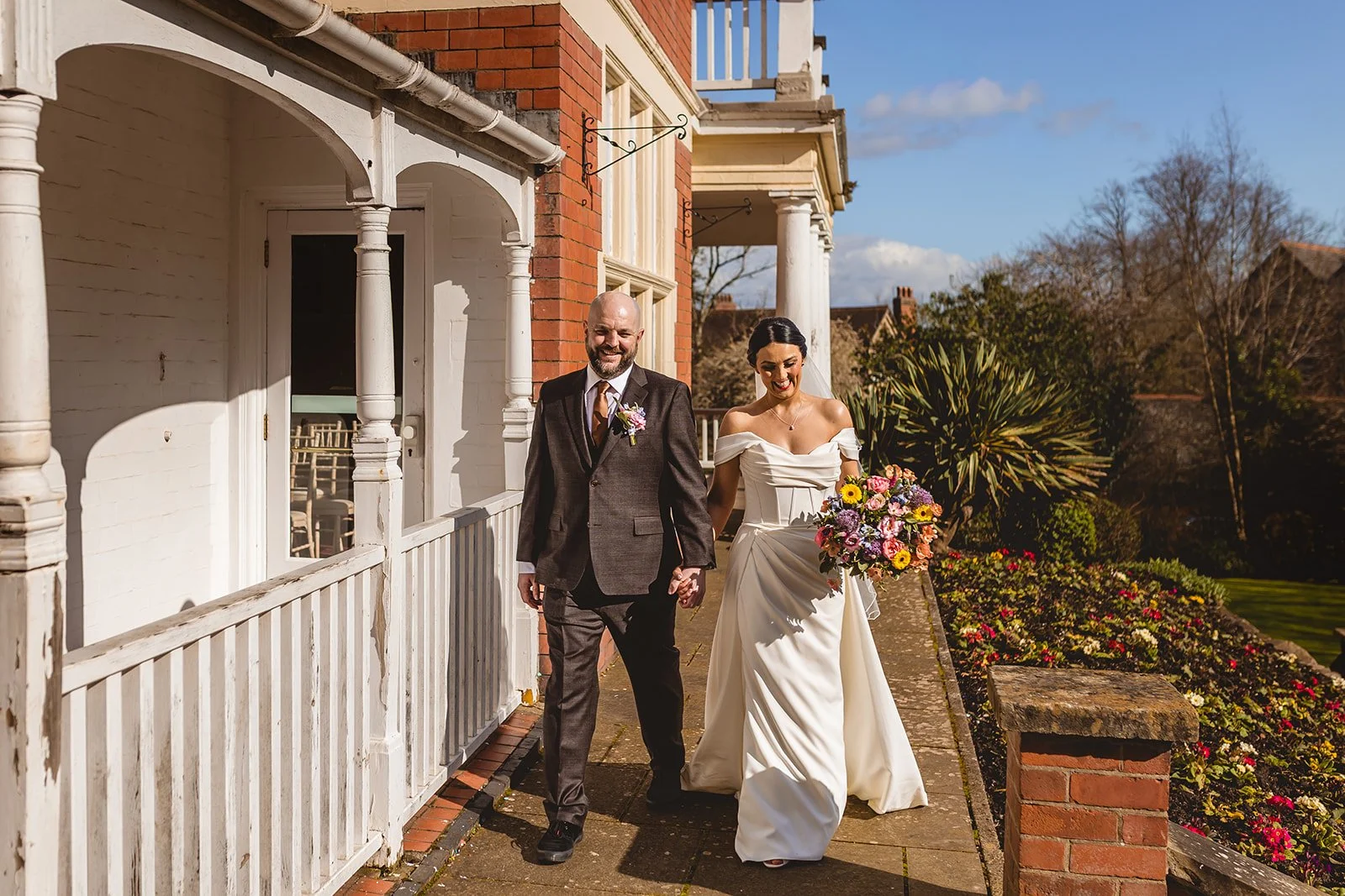 A happy bride and groom strolling candidly outside Newport registry office on a bright spring day.