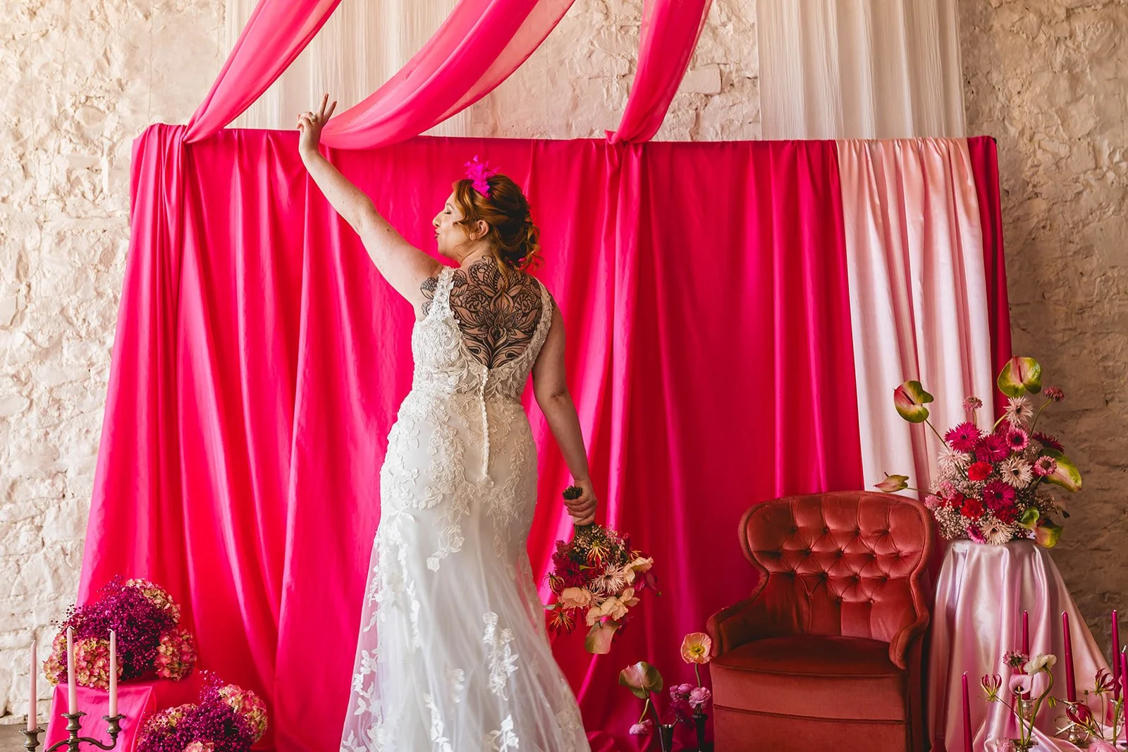 alternative, tattooed welsh bride poses in front of colourful pink background at rosedew farm