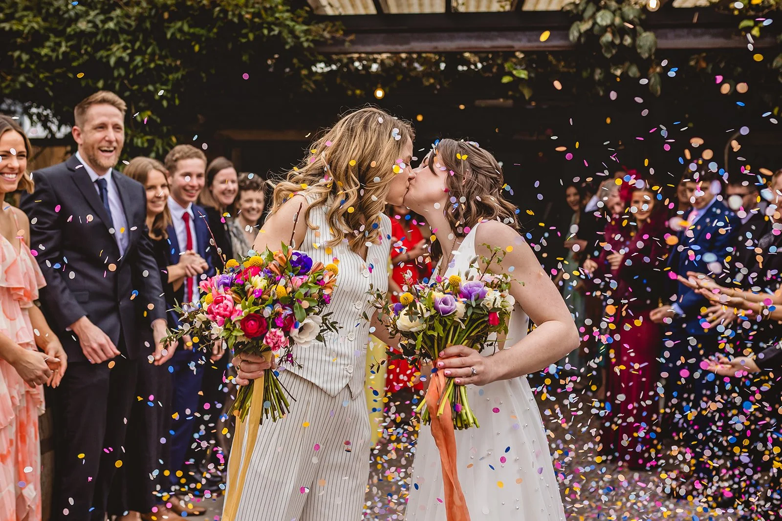 lgbtq+ couple stop for a kiss during their confetti run on their wedding day at the shack revolution