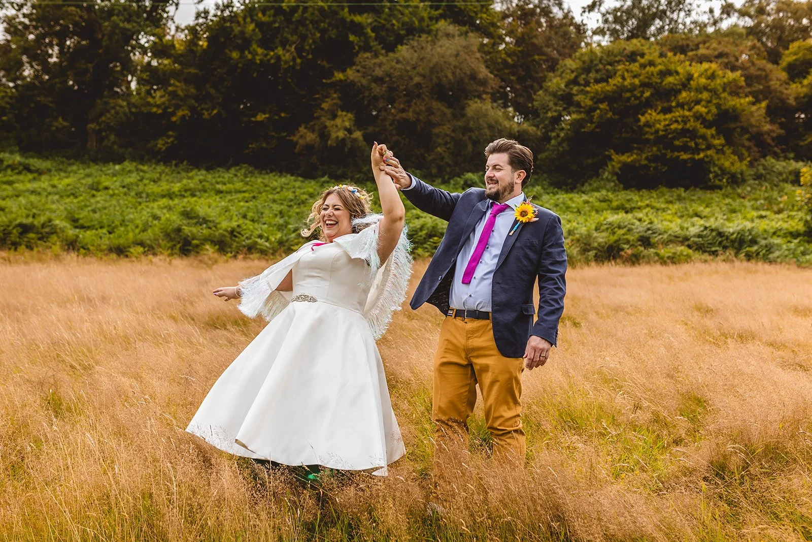 An alternative styled couple dance in a field on their colourful festival wedding day at The sheepshed