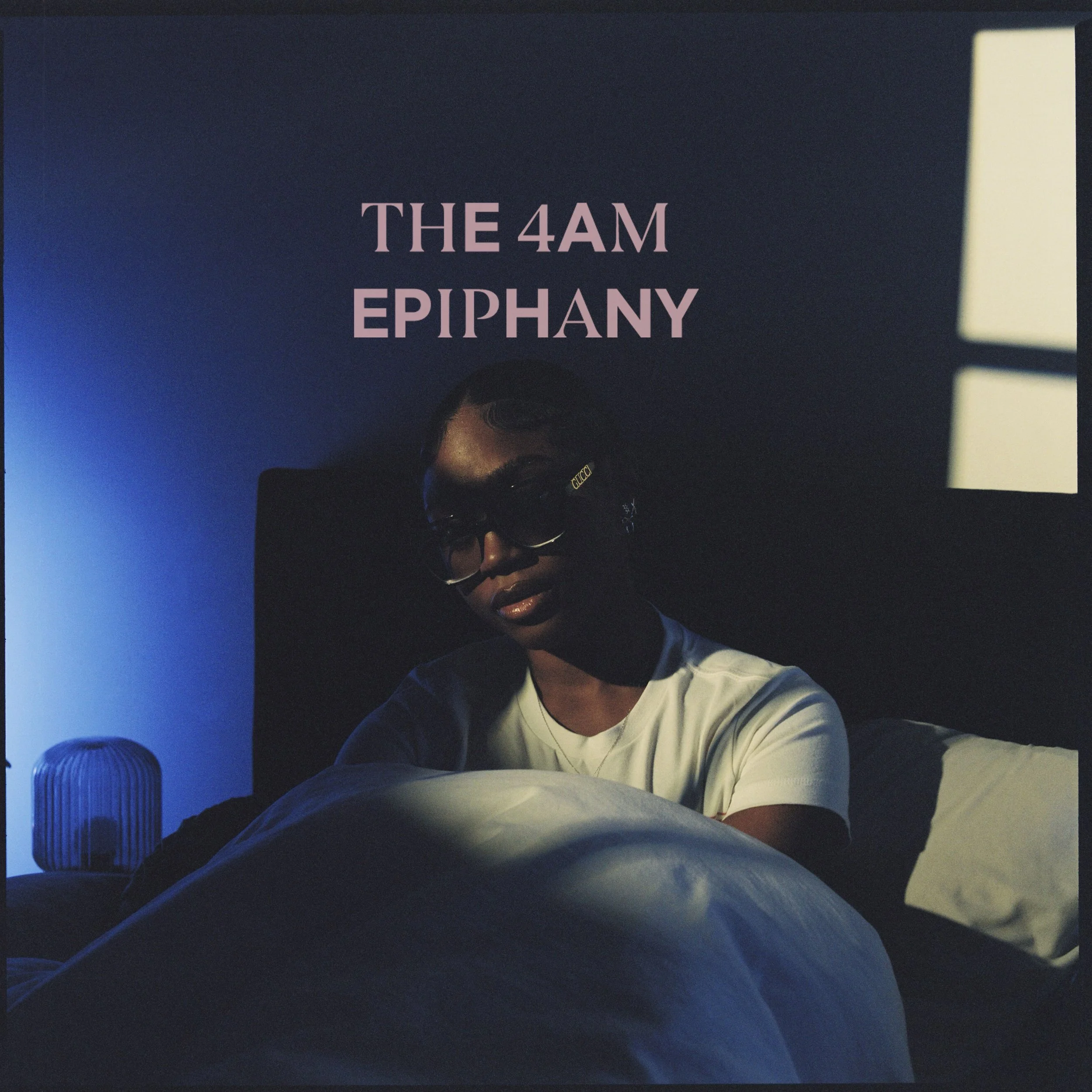 A woman wearing sunglasses sitting up in bed with a dark headboard in a dimly lit room. A blue light on a nightstand on the left and a window with light coming through on the right. Overlaid text reads 'The 4AM Epiphany.'