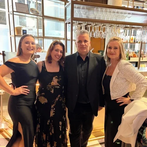 Four women and one man standing together in a restaurant or bar, smiling at the camera.