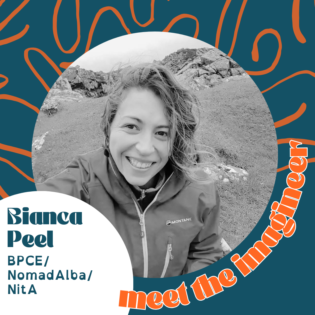 Black and white portrait of Bianca Peel smiling outdoors with rocky terrain and mountains in the background, wearing a jacket.