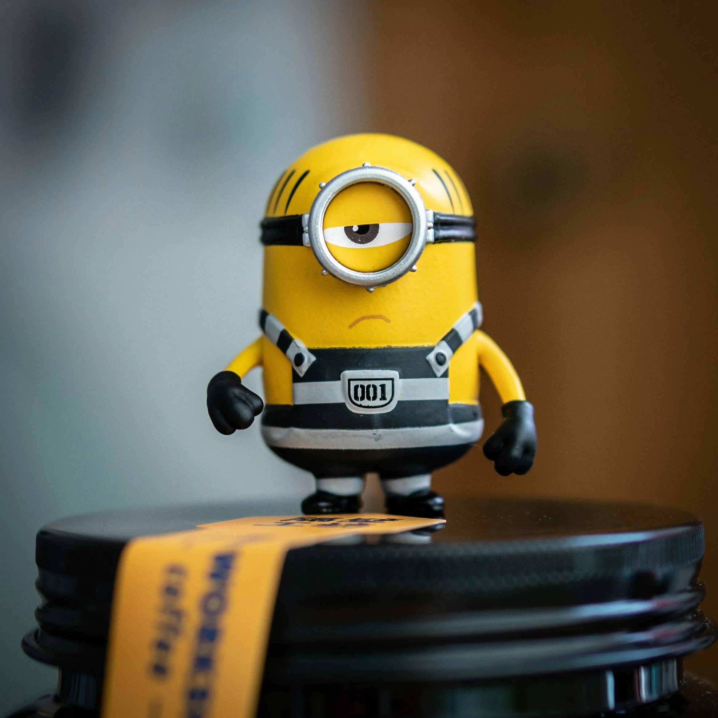Figurine de Minion habillé comme un criminel, portant un collier de prison et une combinaison à rayures, avec un œil unique.