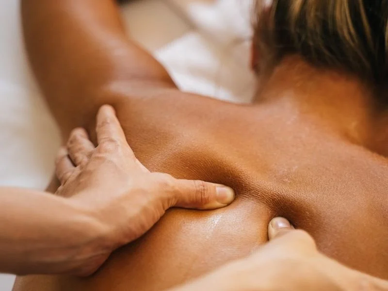 Une personne reçoit un massage des épaules dans un cadre relaxant.