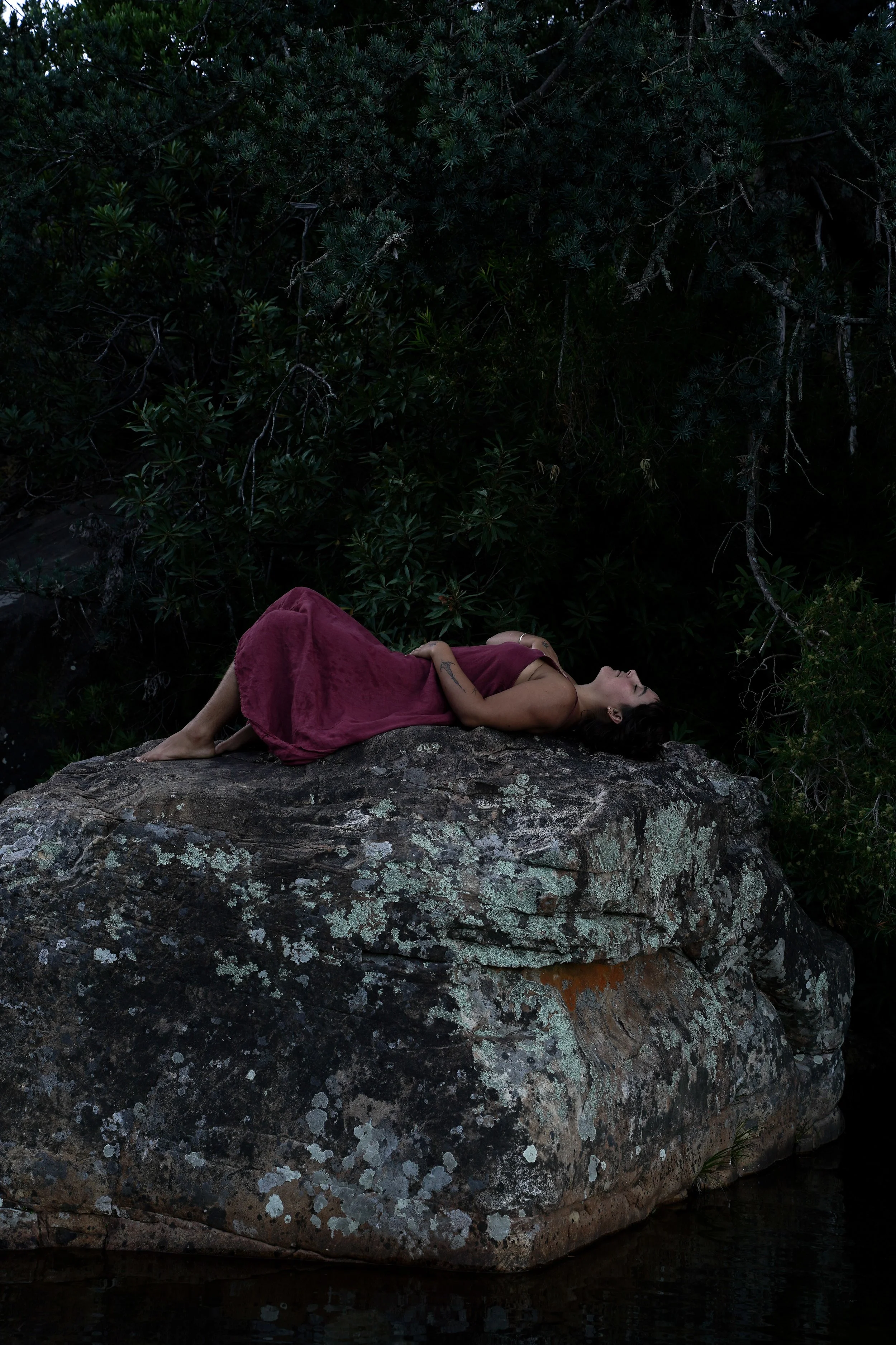 Woman lying on a rock in a pink dress. 