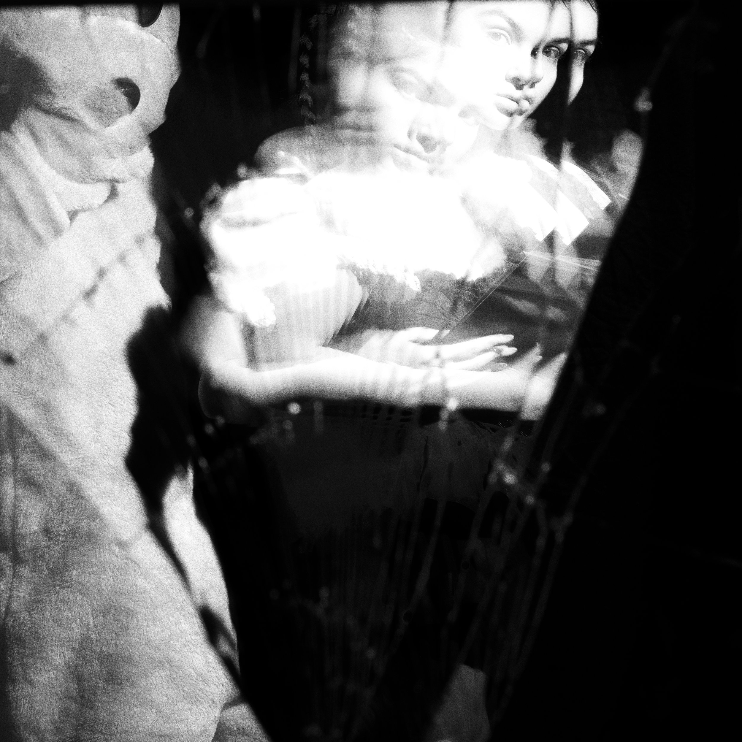 Black-and-white photo of a mannequin or sculpture of a woman with multiple blended images of her face, creating a ghostly or layered effect.