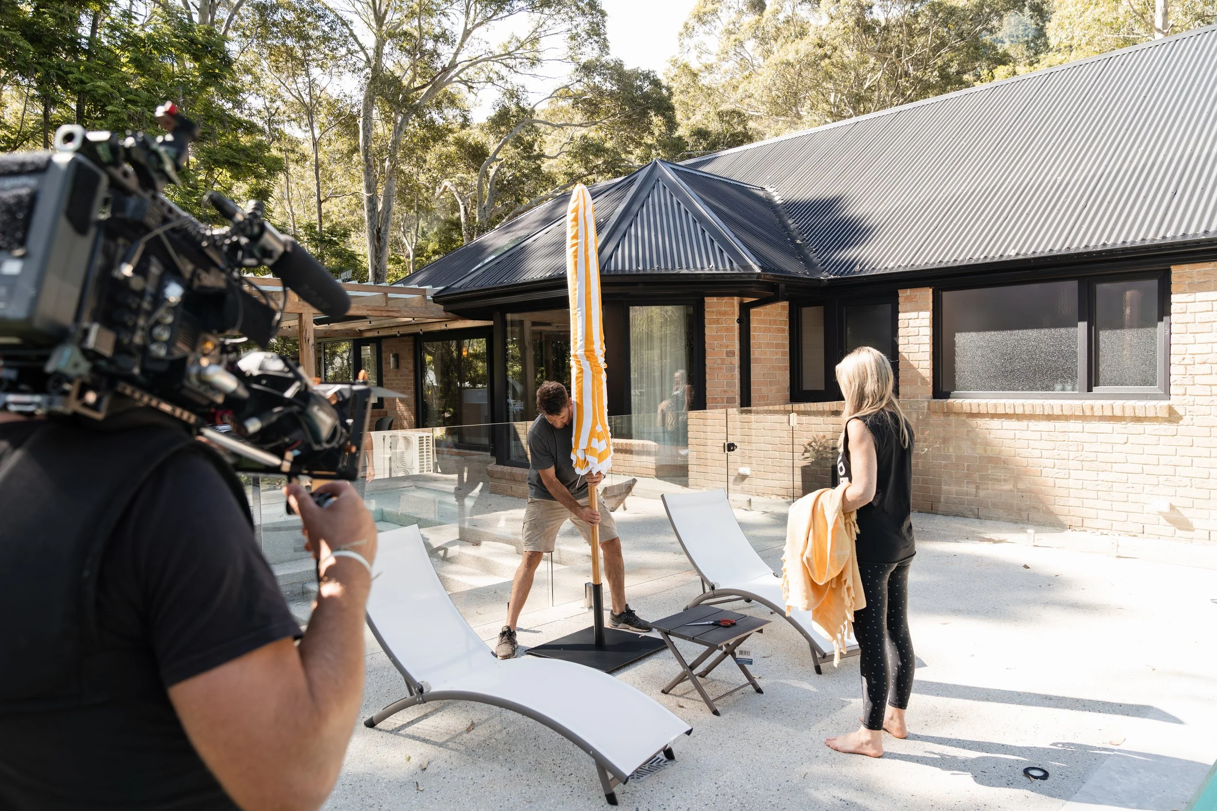 A behind-the-scenes view of Rachel and Ryan styling the pool area while filming their TV show Holiday Home Makeover with Rachel & Ryan, The R&R Design Co.