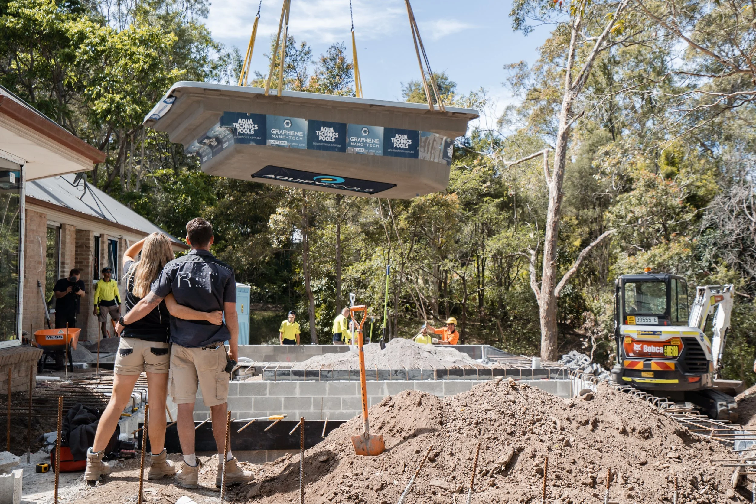 Rachel and Ryan with their big Aquify Pool with a bow around it and on a crane while filming their TV show Holiday Home Makeover with Rachel & Ryan, The R&R Design Co.