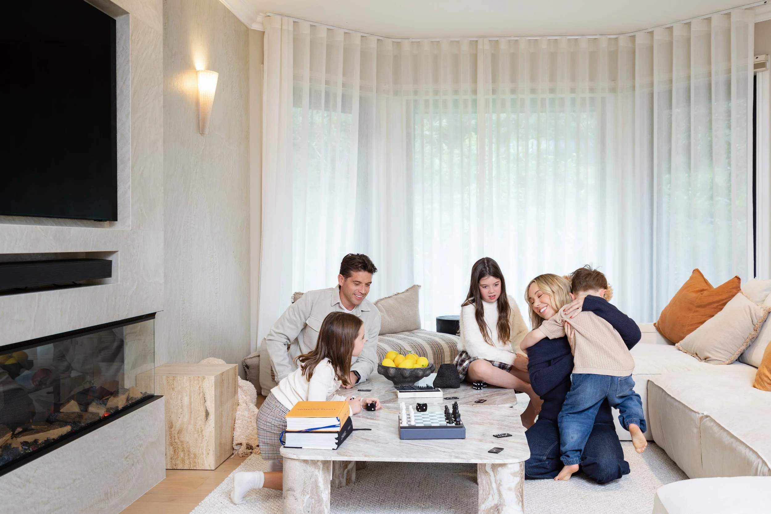 Rachel and Ryan and their kids playing in their luxury contemporary inspired living room while filming their TV show Holiday Home Makeover with Rachel & Ryan, The R&R Design Co.