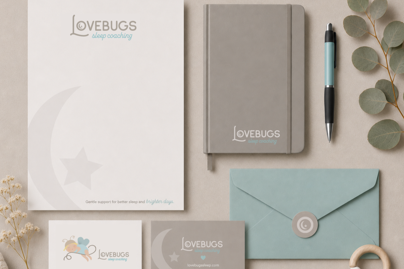 Flat lay of sleep coaching materials with LOVEBUGS branding, including a white sheet with moon and star illustration, gray and blue envelopes, a gray notebook, a blue pen, eucalyptus leaves, and a small card with a sleeping bug illustration.