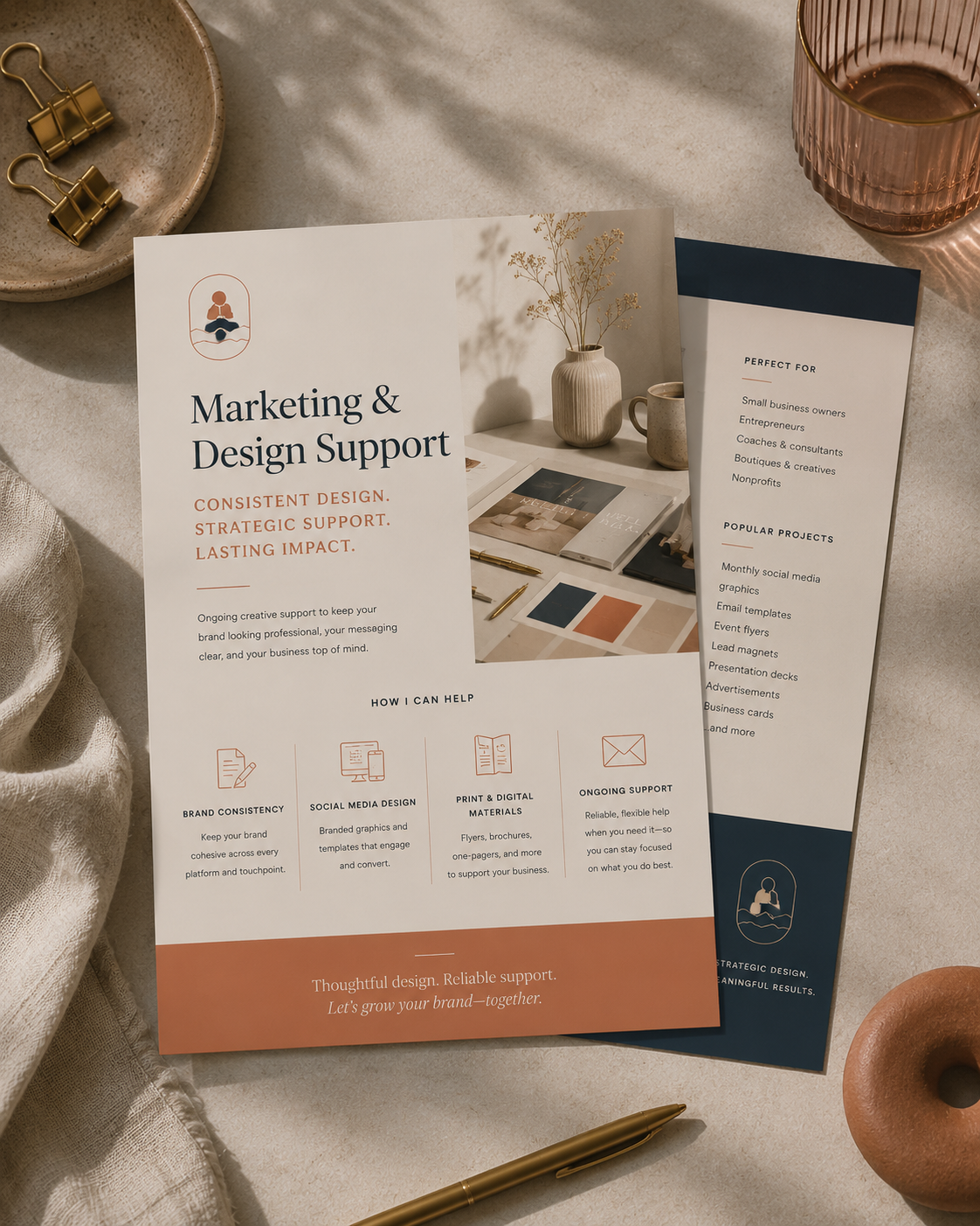 Brochures about marketing and design support with a minimalistic aesthetic, featuring text about branding, social media, print, and ongoing support, placed on a neutral surface with a gold pen, a glass of pink smoke, and natural decor elements.