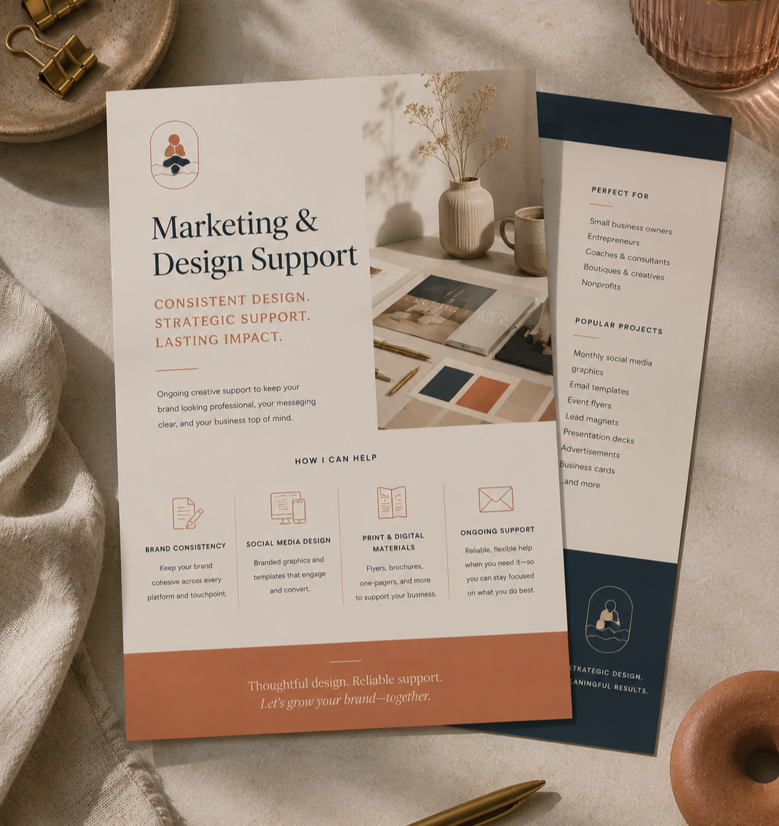 Brochure offering marketing and design support services, including brand consistency, social media design, print and digital materials, and ongoing support, on a beige surface with gold pen, fabric, and decorative items.