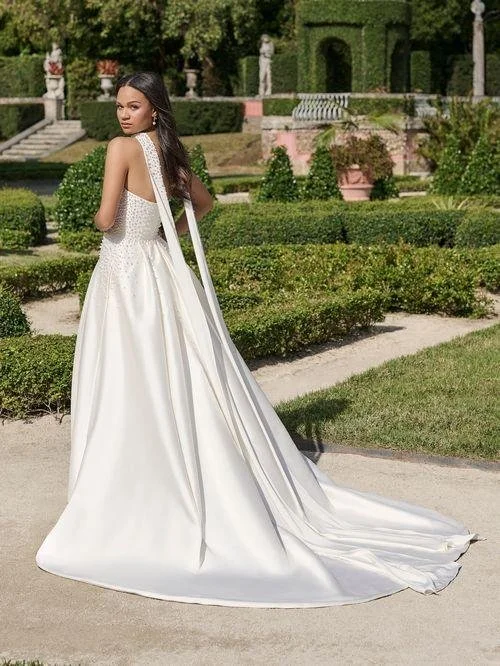 Bride wearing long satin wedding gown with scarf around neck and down train