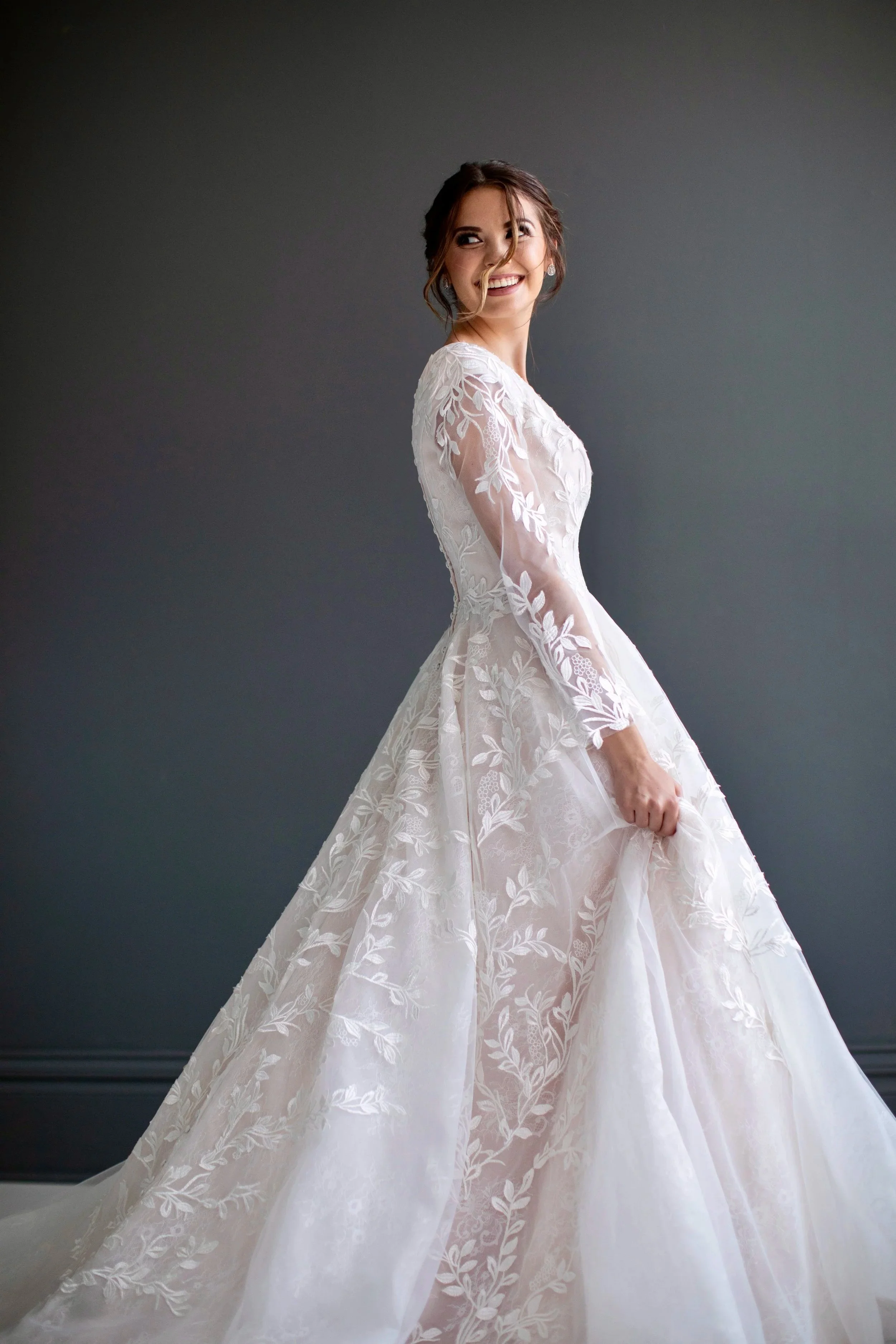 Smiling bride wearing long sleeve wedding gown.