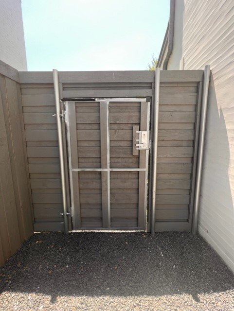 A security gate with a latch, set in a fenced area