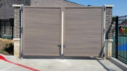 Closed sliding gate with brick pillars and black fencing on both sides.