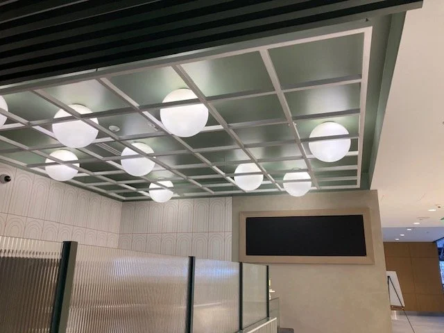 Ceiling with square grid pattern and round white light fixtures in an indoor space.