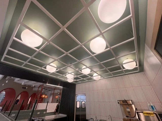 Ceiling with grid pattern and round light fixtures in a modern interior space.