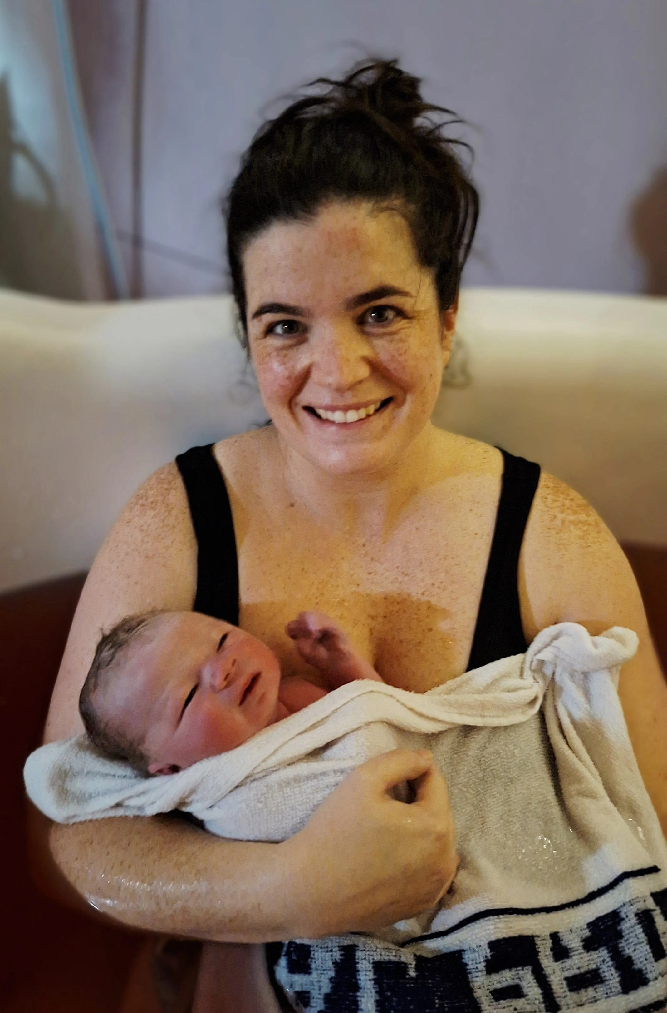 smiling woman with newborn in birthing pool