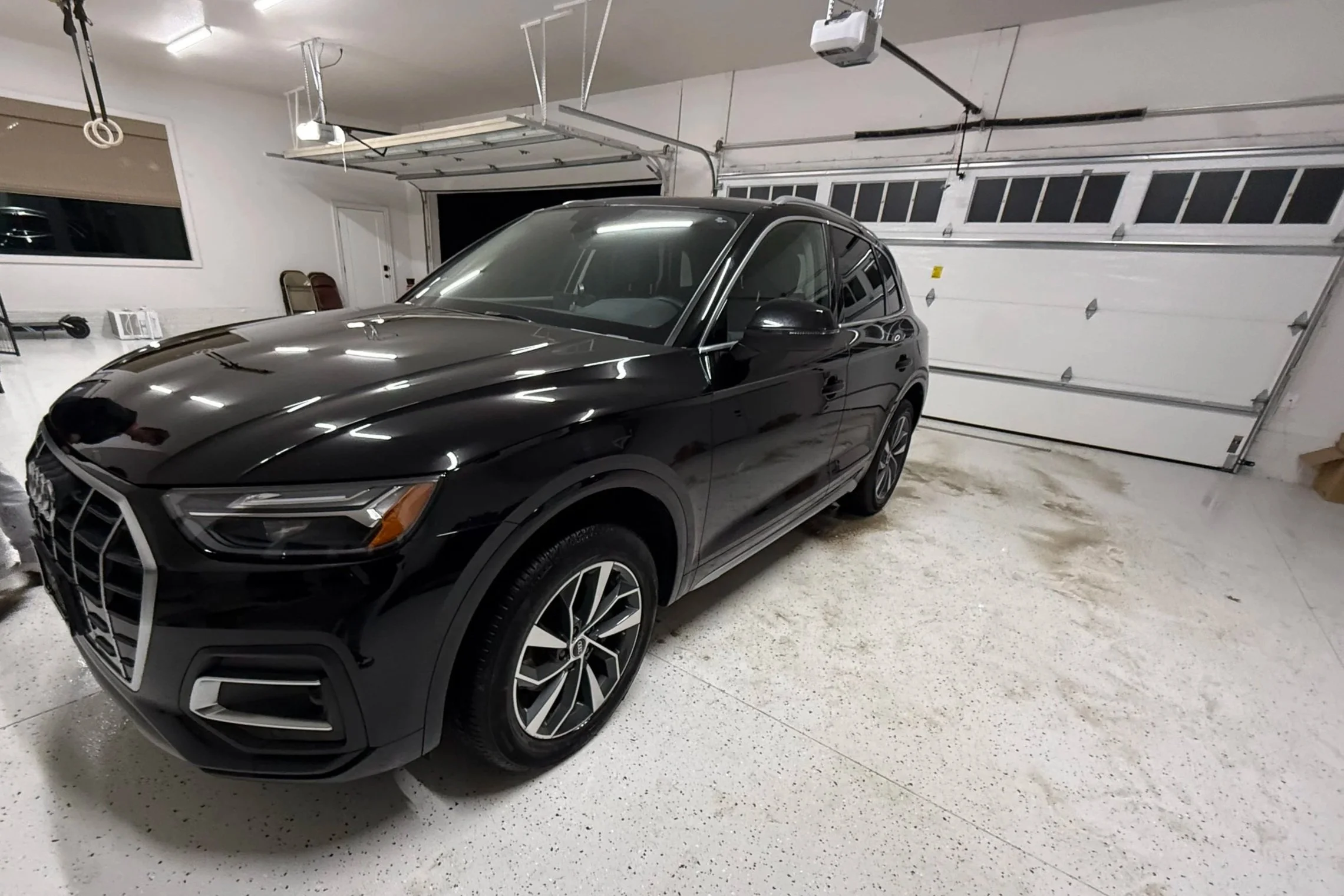 Black SUV parked inside a spacious, well-lit garage with white walls and a closed garage door.