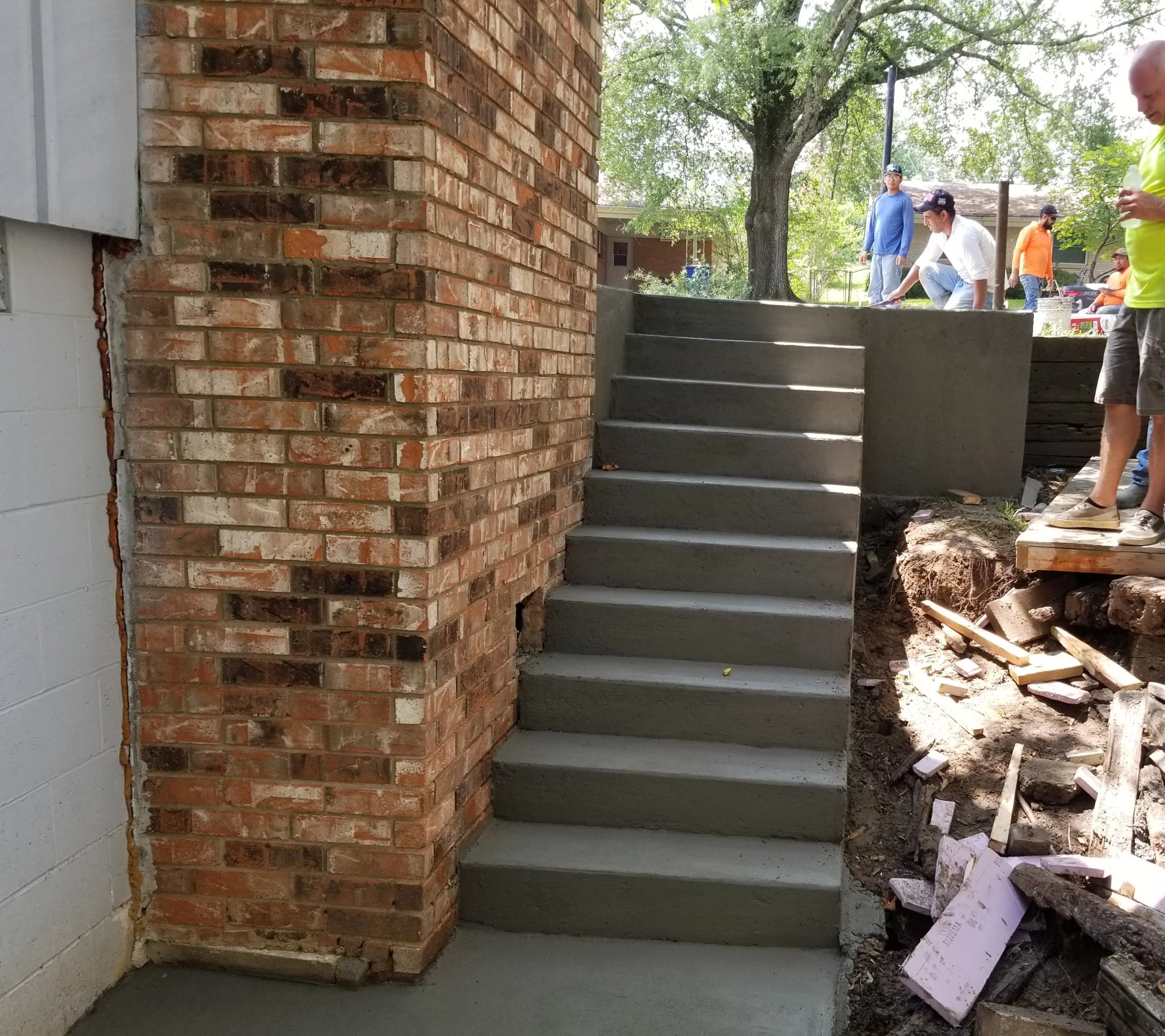Custom concrete stairs connecting a residential driveway to a backyard patio and around a chimney.