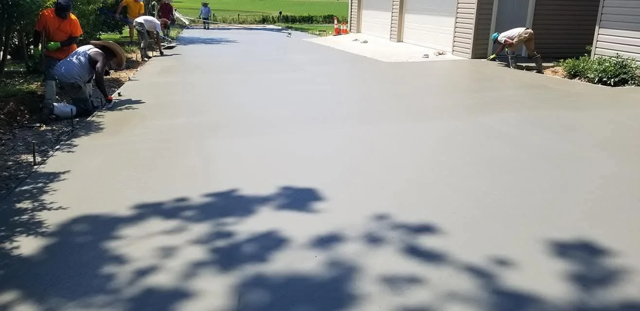 People pouring and spreading concrete in a driveway during construction or renovation.