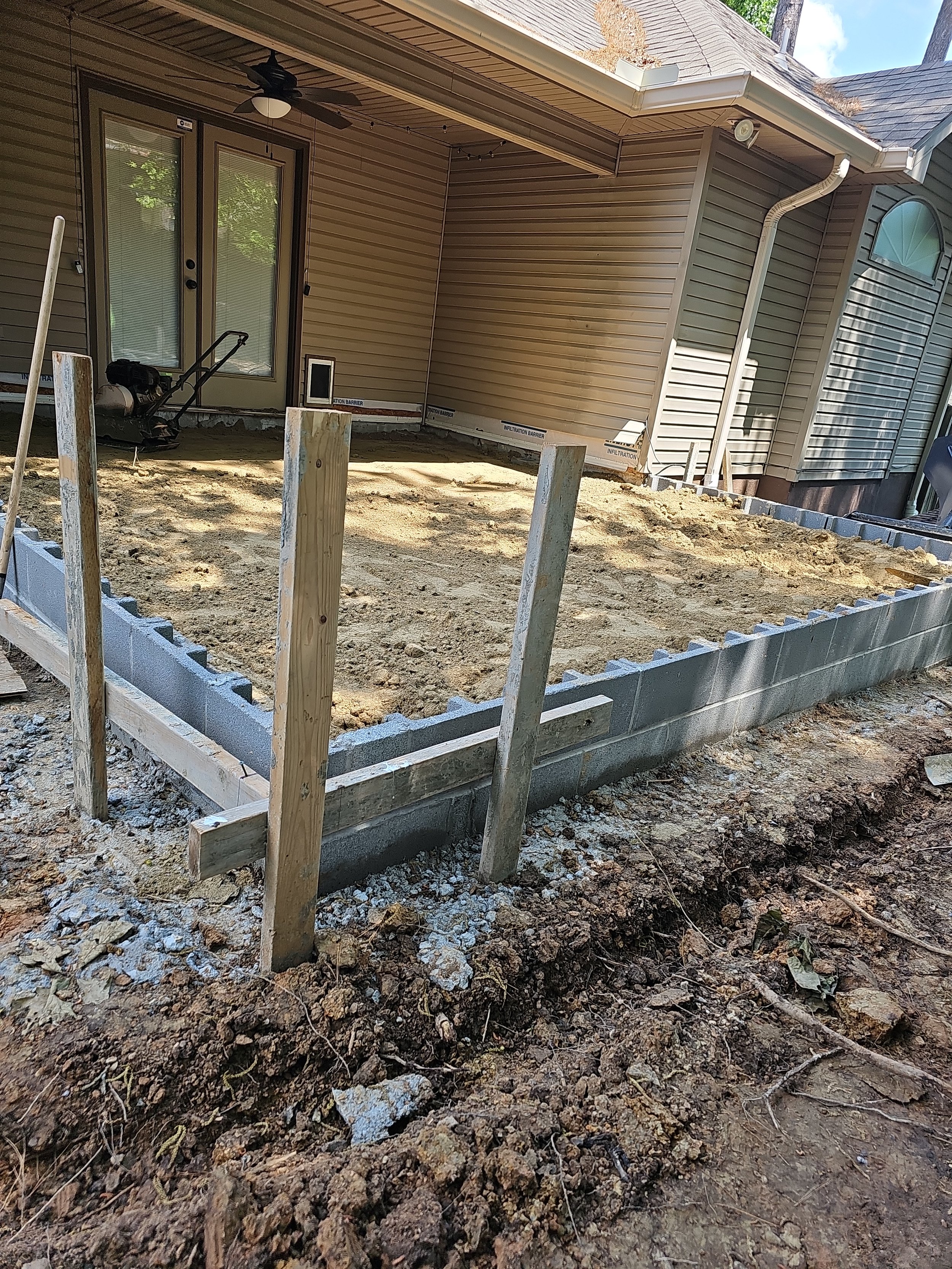 Backyard with dirt foundation and cinder block boundary, outdoor construction site.