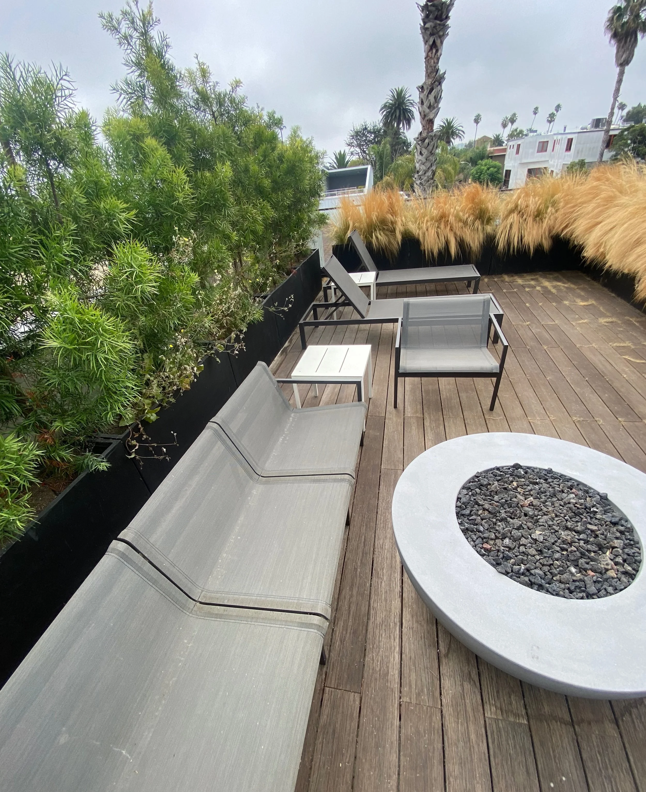 Clean rooftop deck with outdoor fire pit and modern patio furniture, maintained as part of luxury property care services.
