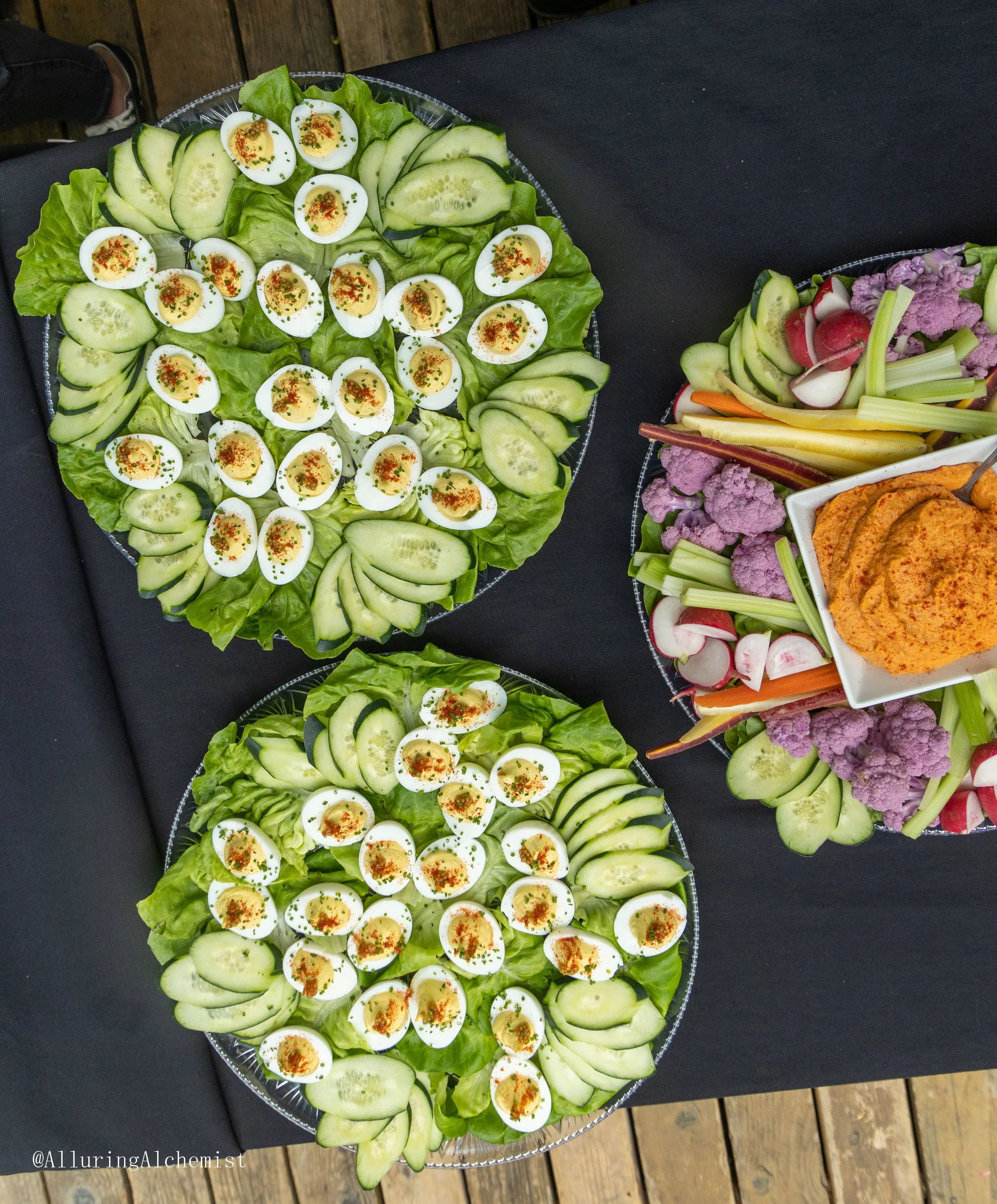 A platter of cut cucumbers, halved boiled eggs sprinkled with paprika and herbs on a bed of lettuce, decorated for a meal or gathering.