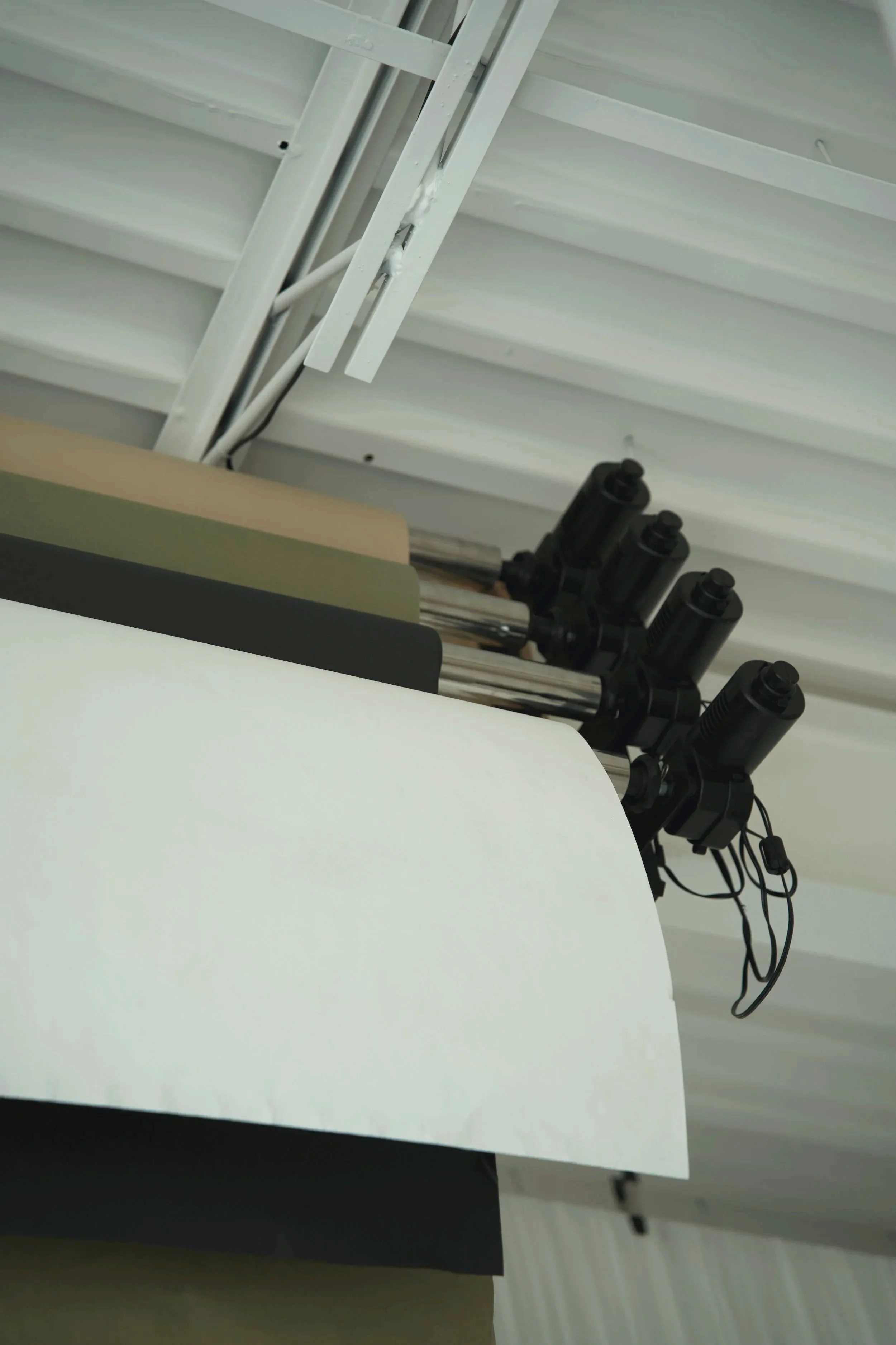 Black binoculars mounted on a white and black stand in an indoor space with a metal ceiling.