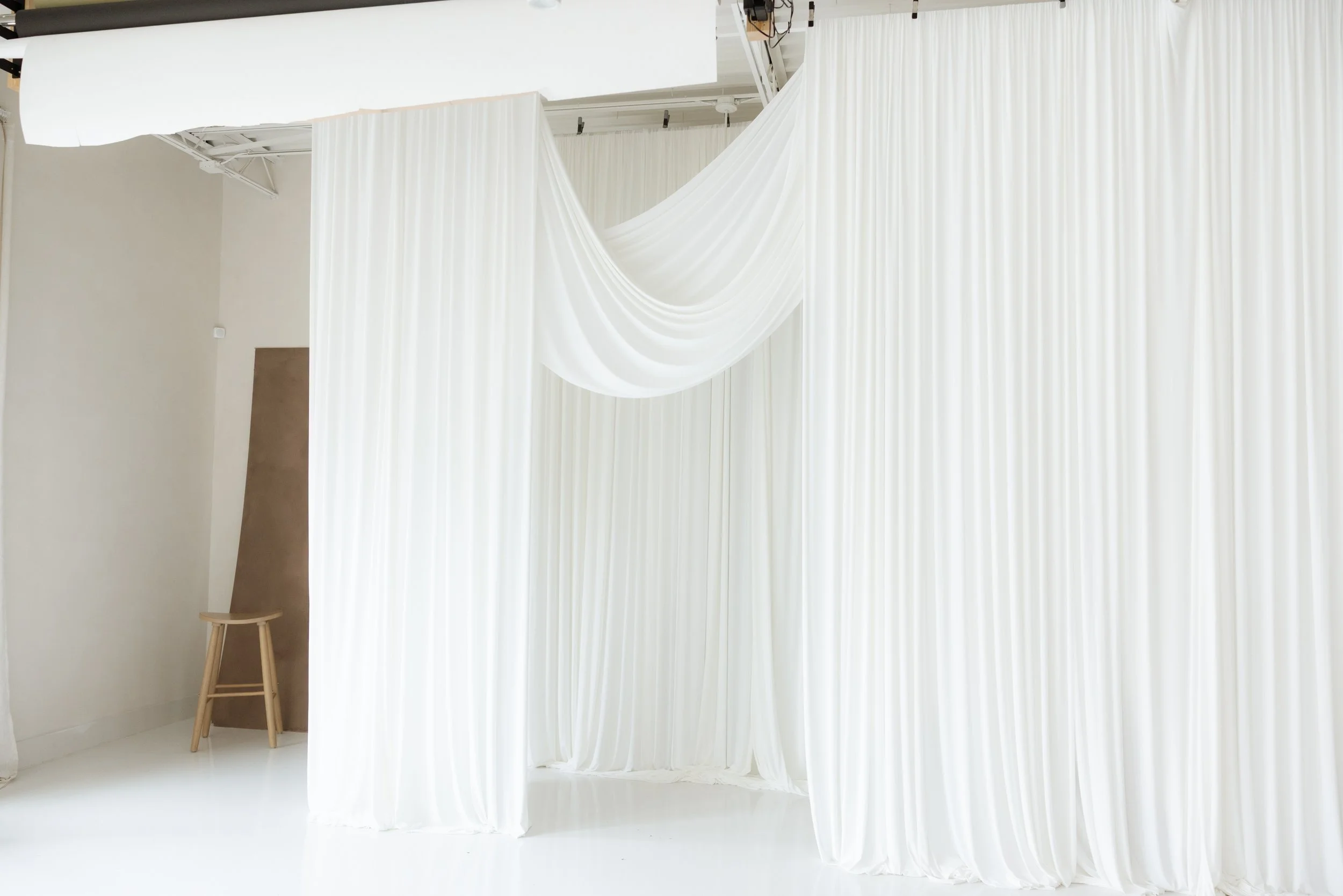 White pleated curtains with a draped fabric in a bright, minimalist room.