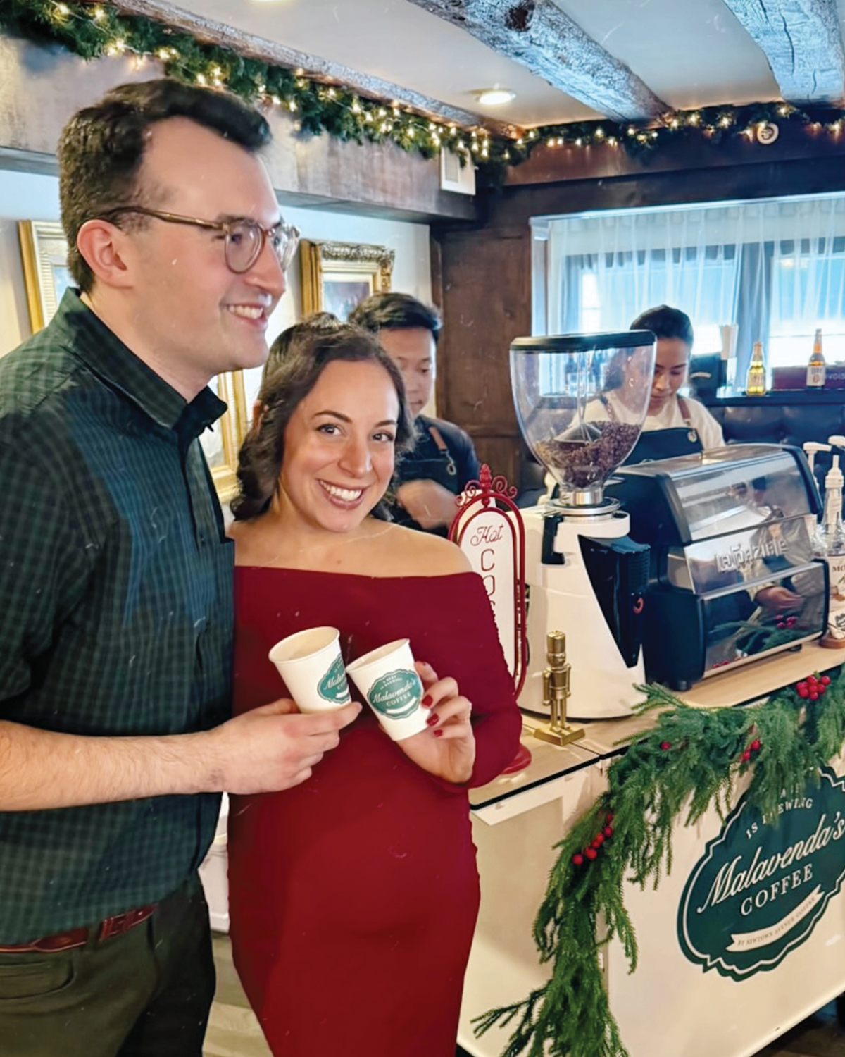 A couple enjoying hot drinks served by Aries and Anna for a holiday market-themed baby shower in the Greater New York area