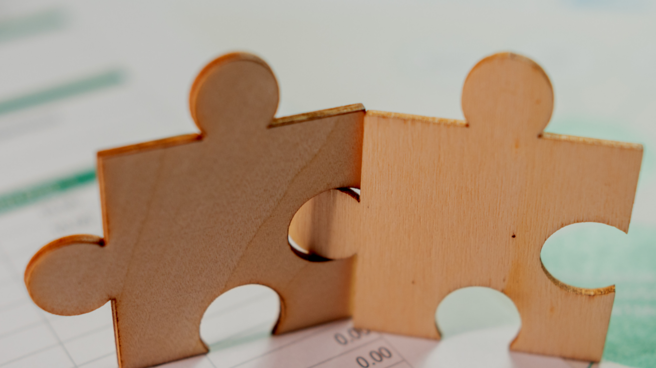Two interlocking wooden puzzle pieces placed on a document or form.