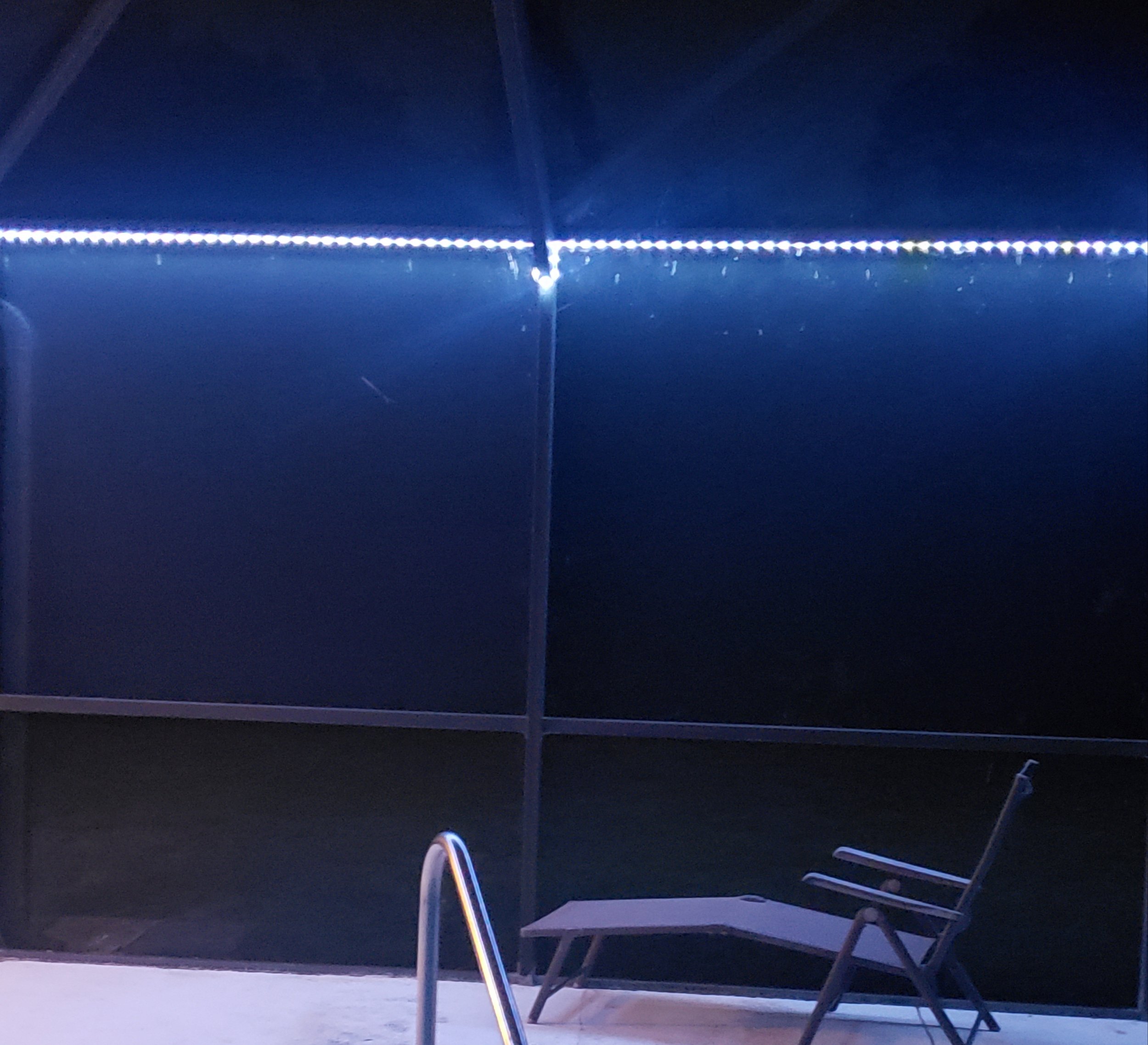 A pool area illuminated by blue LED lights at night.